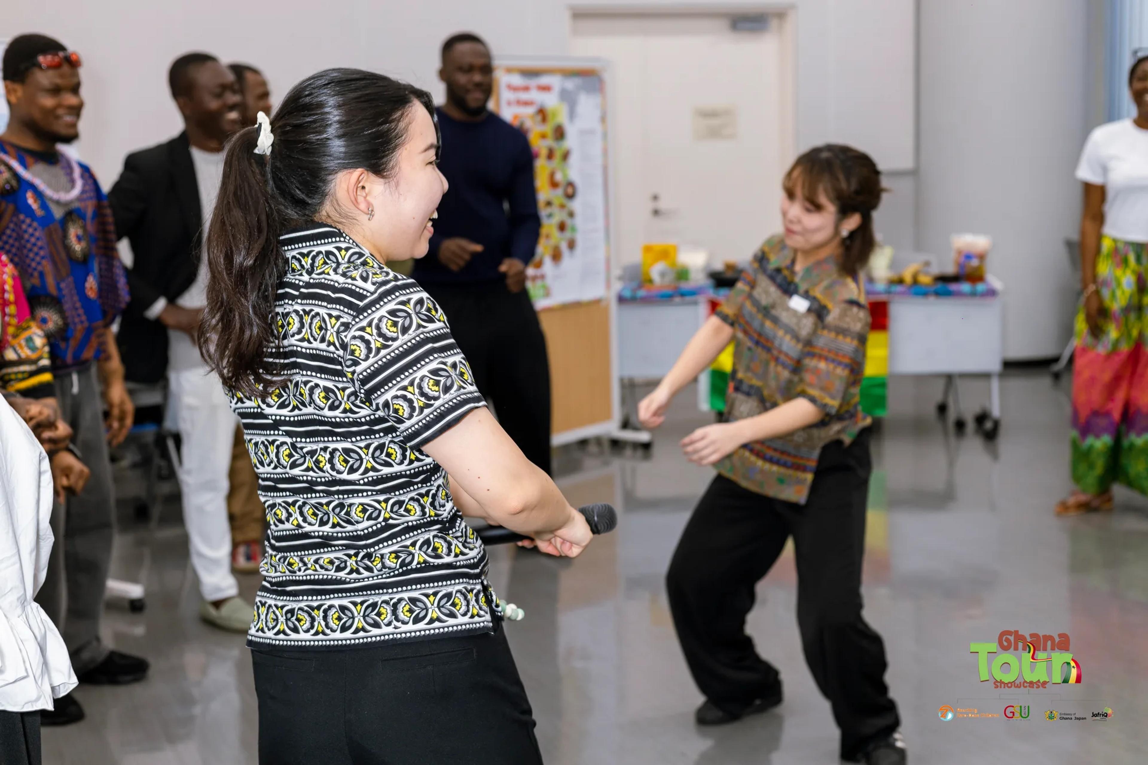 Two young women dance playfully on the floor of the cultural expo