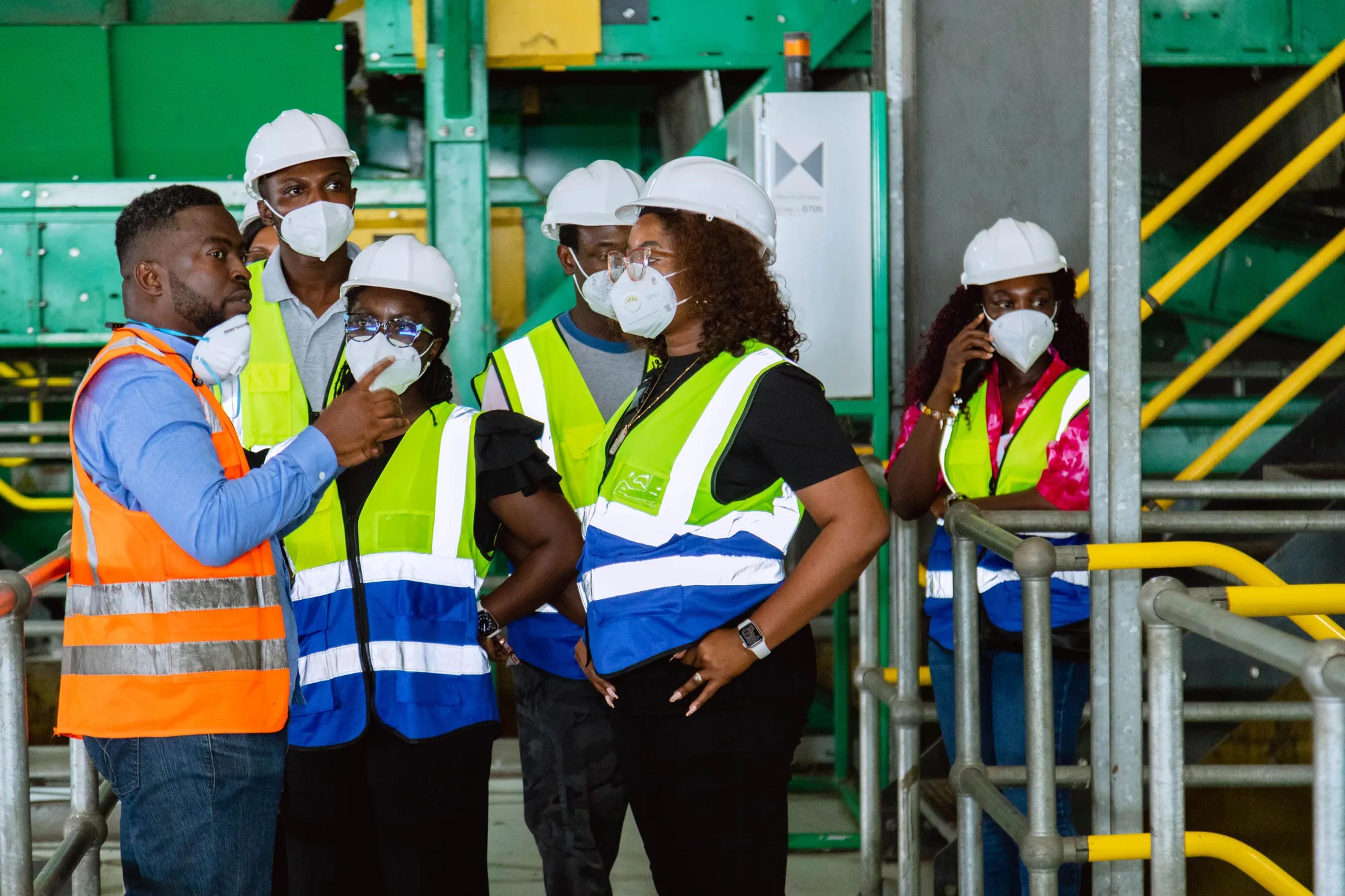 The team in hard hats and vests discussing the sorting line with a guide