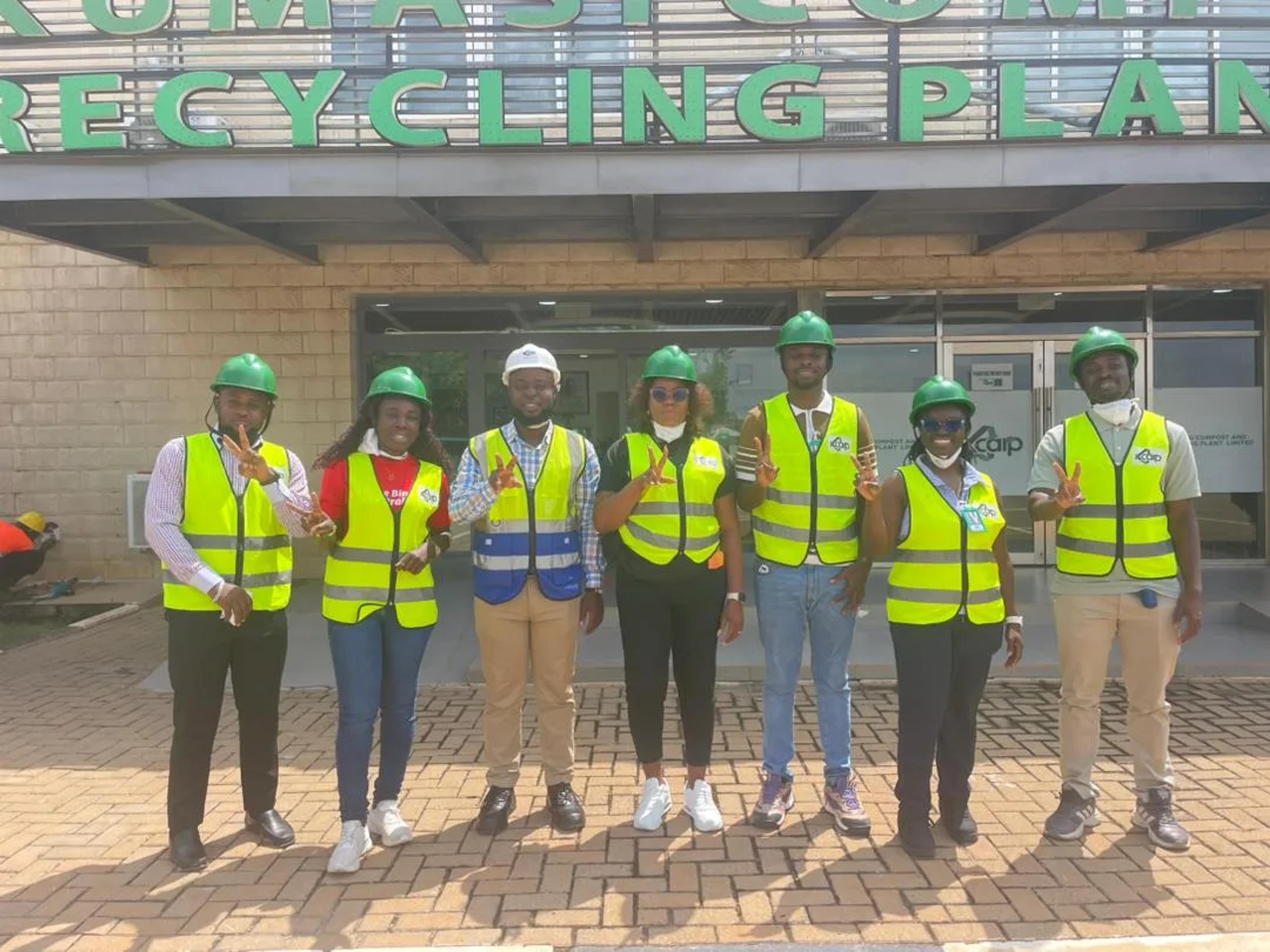 The team in vests and helmets in front of the Kumasi Compost and Recycling Plant