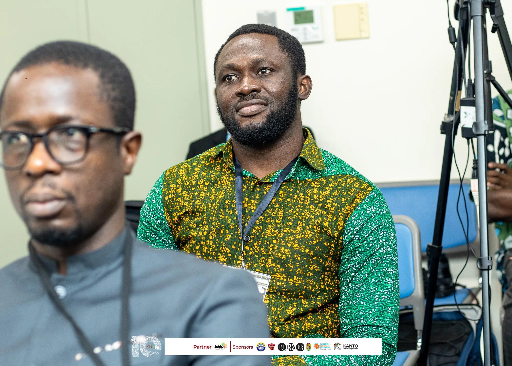 Two attendees listen intently during a symposium presentation