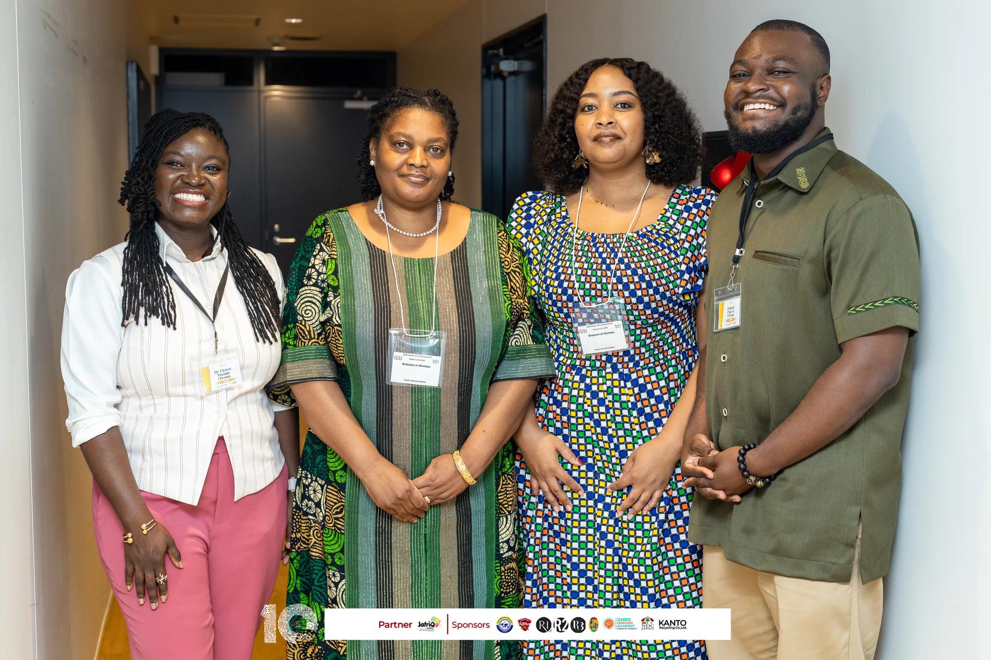 Four attendees in Ghanaian print outfits pose together at the symposium