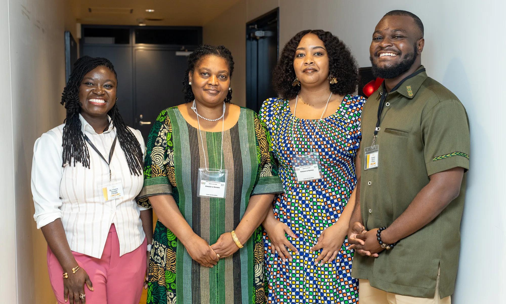 Four attendees in Ghanaian print outfits pose together at the symposium