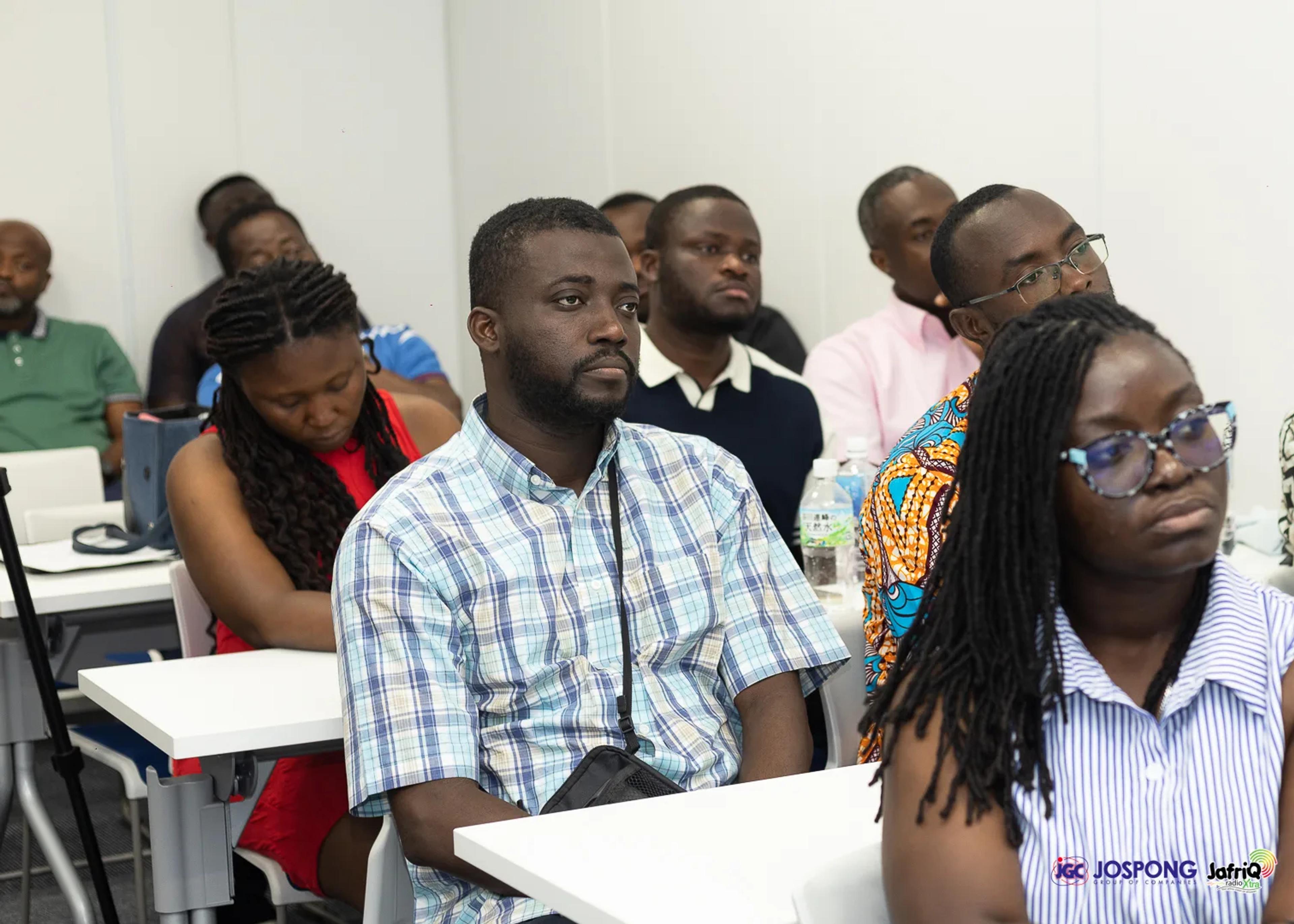 Students follow the presentation from rows of white tables