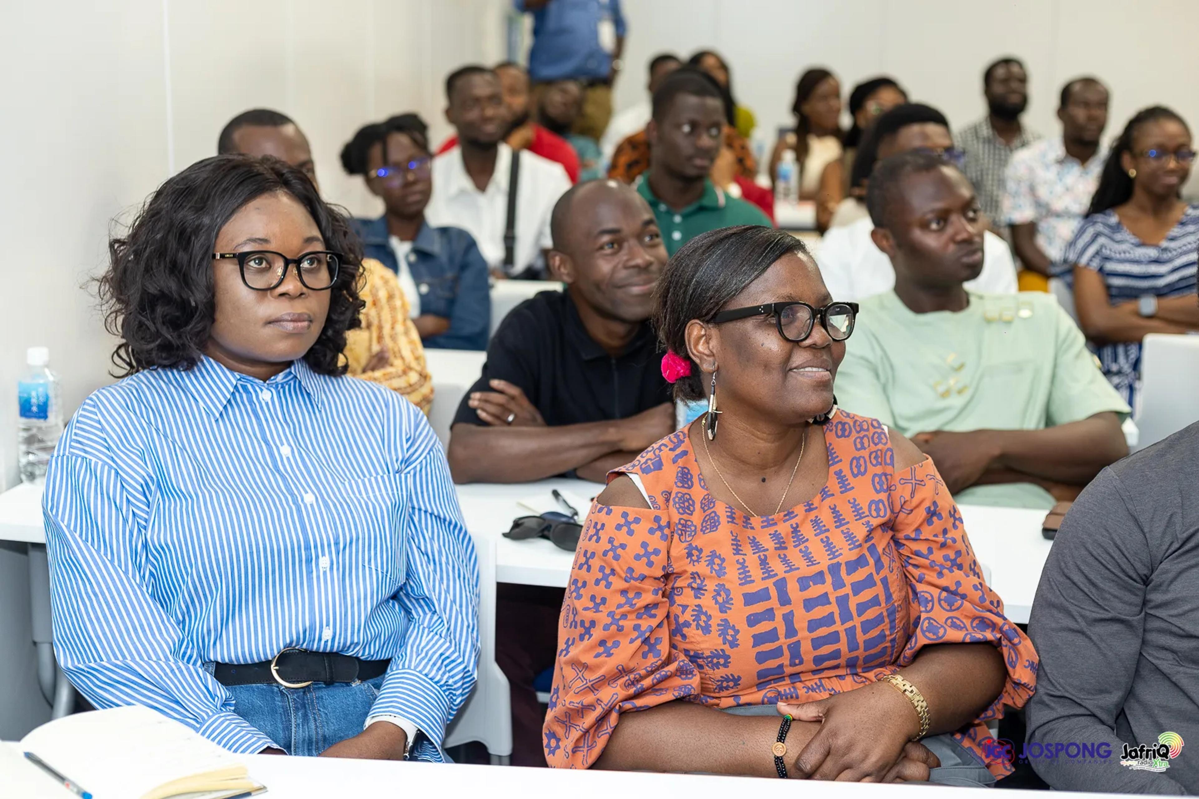Seated students listen attentively at tables in the seminar room