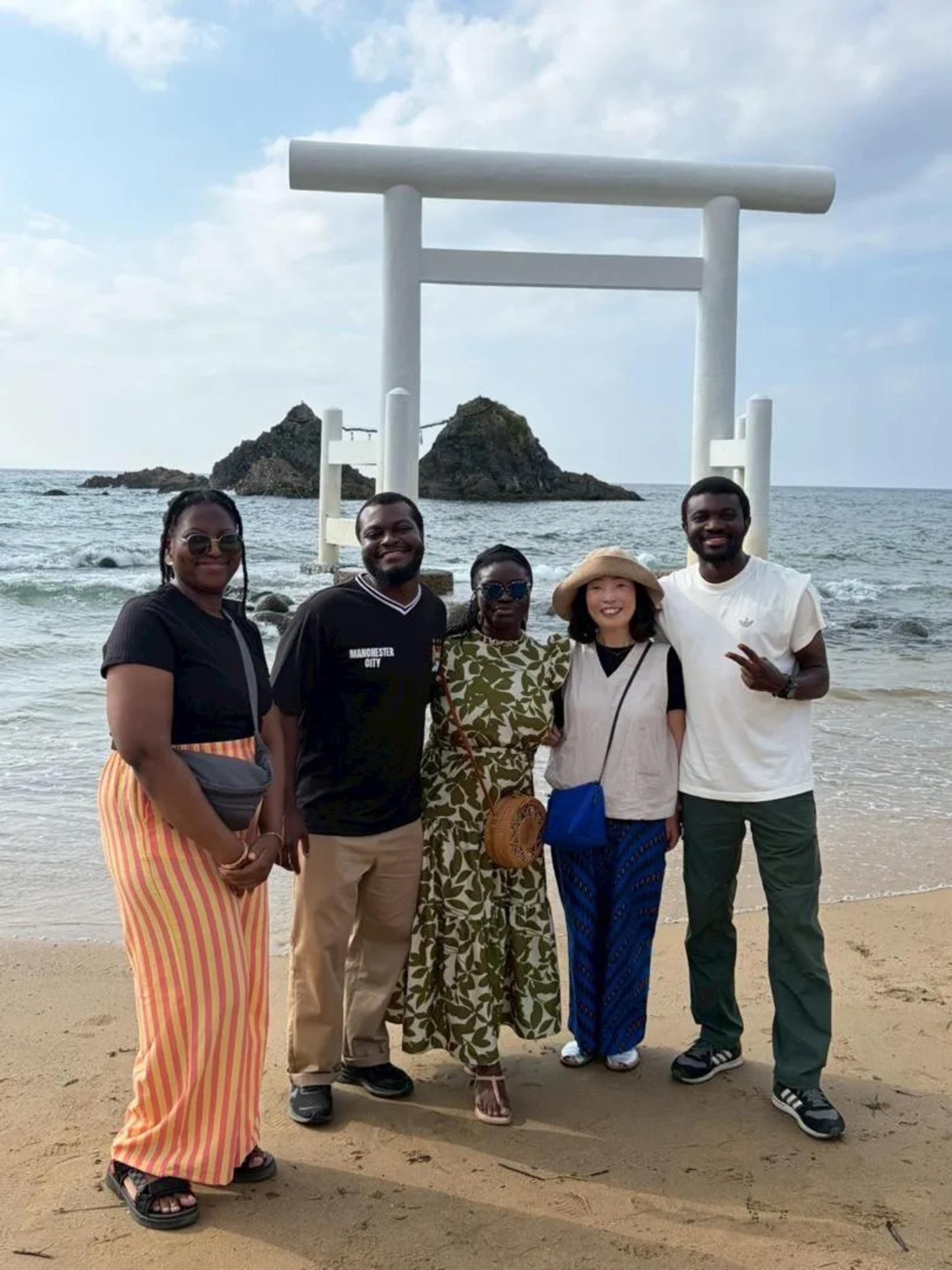 The visiting team with their host by the white torii at Futamigaura, Itoshima