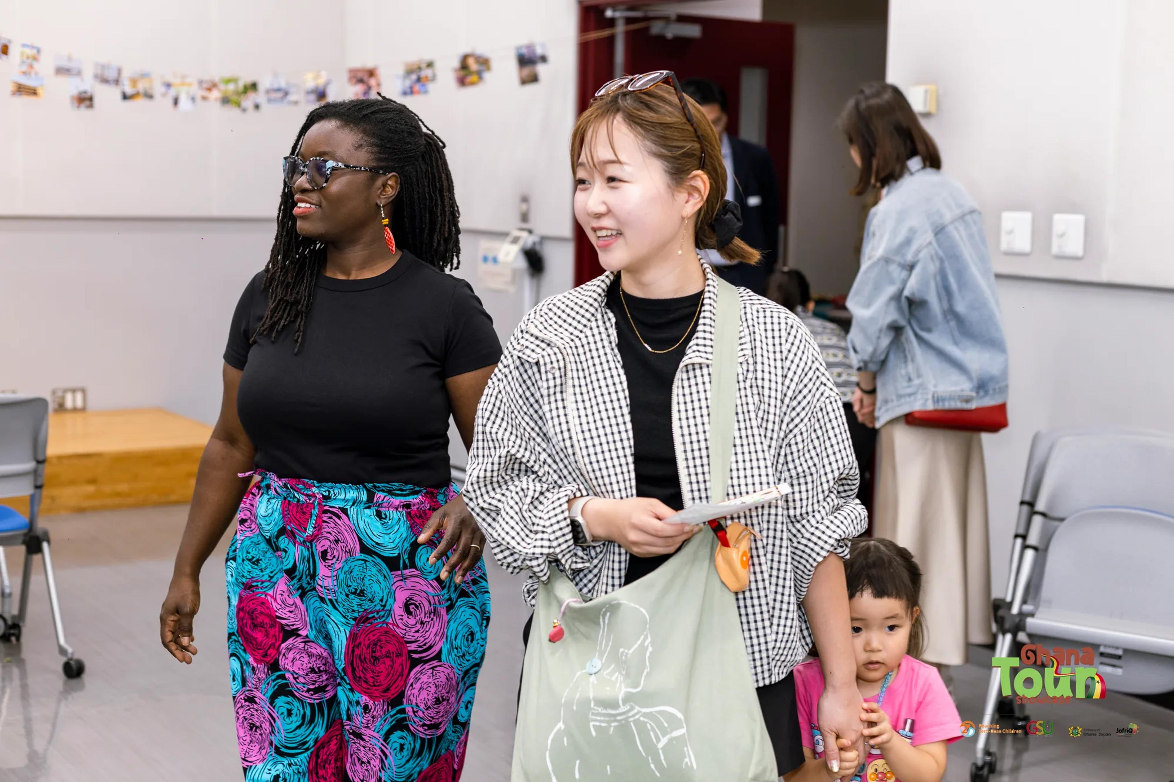 Ghanaian student chats with a visitor and her young child at the expo