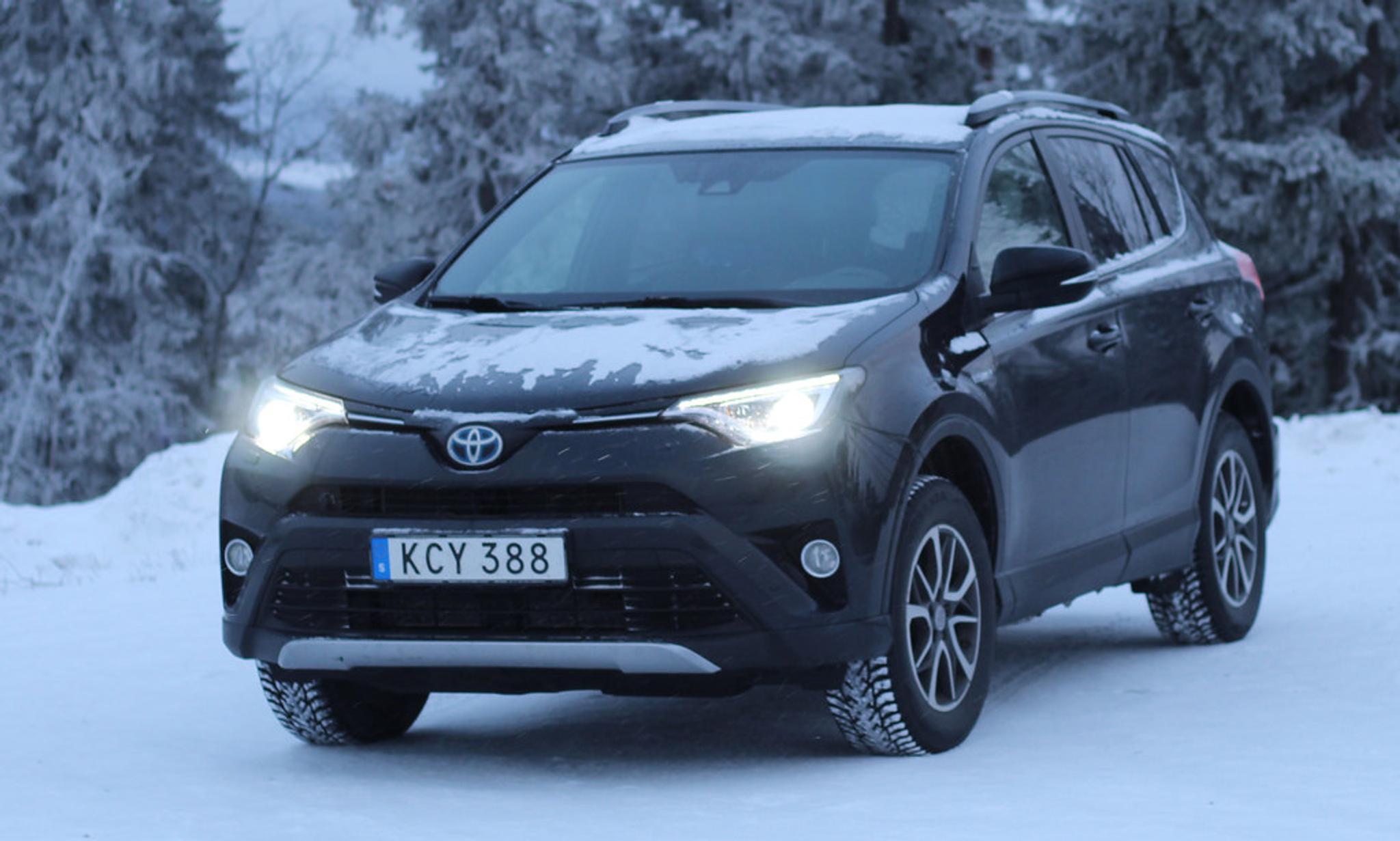 Schwarzer Toyota RAV4 mit eingeschaltetem Licht auf Schnee