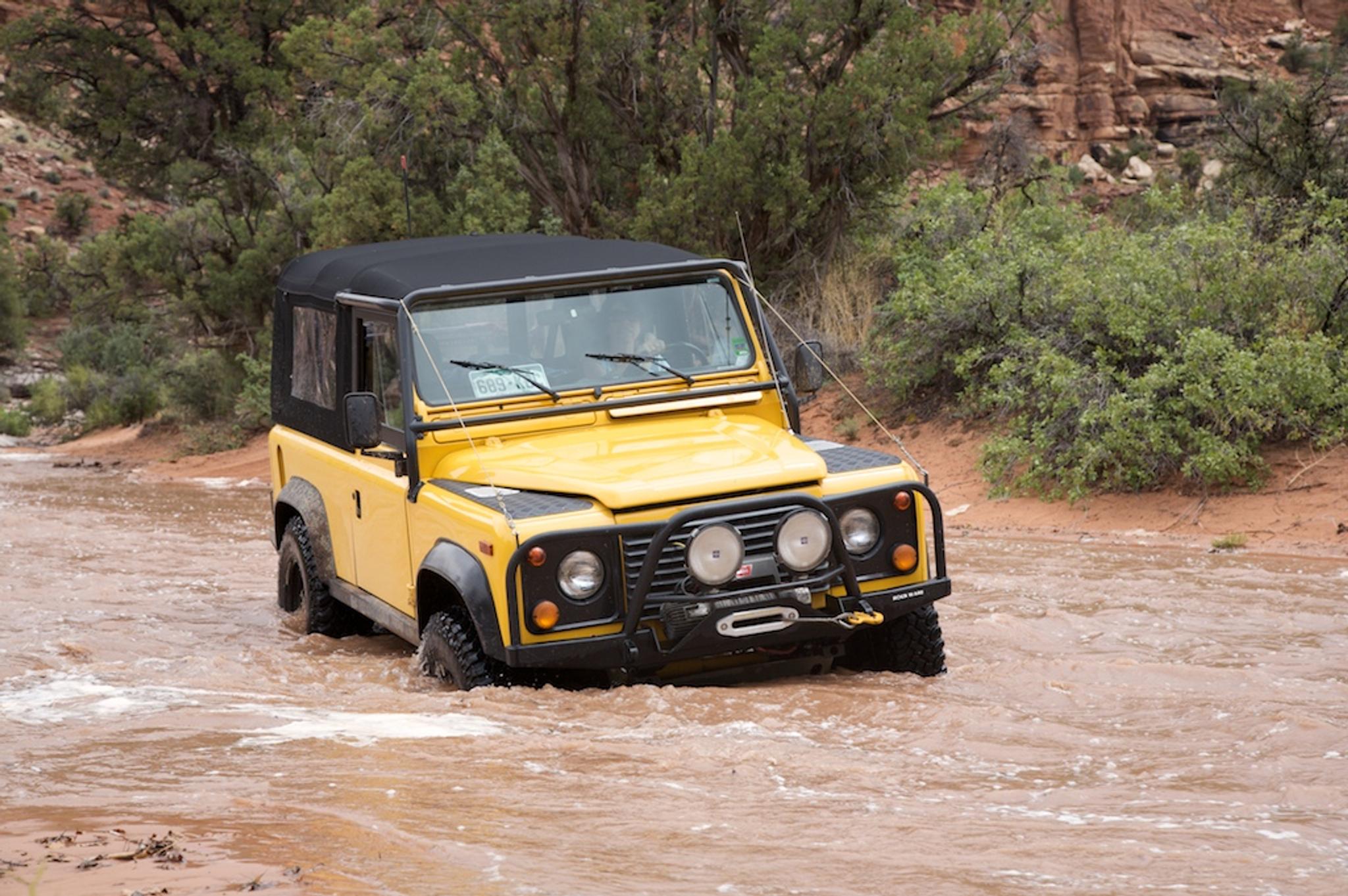 Land Rover defender, rover crossing a river, yellow car driving in rough terrain