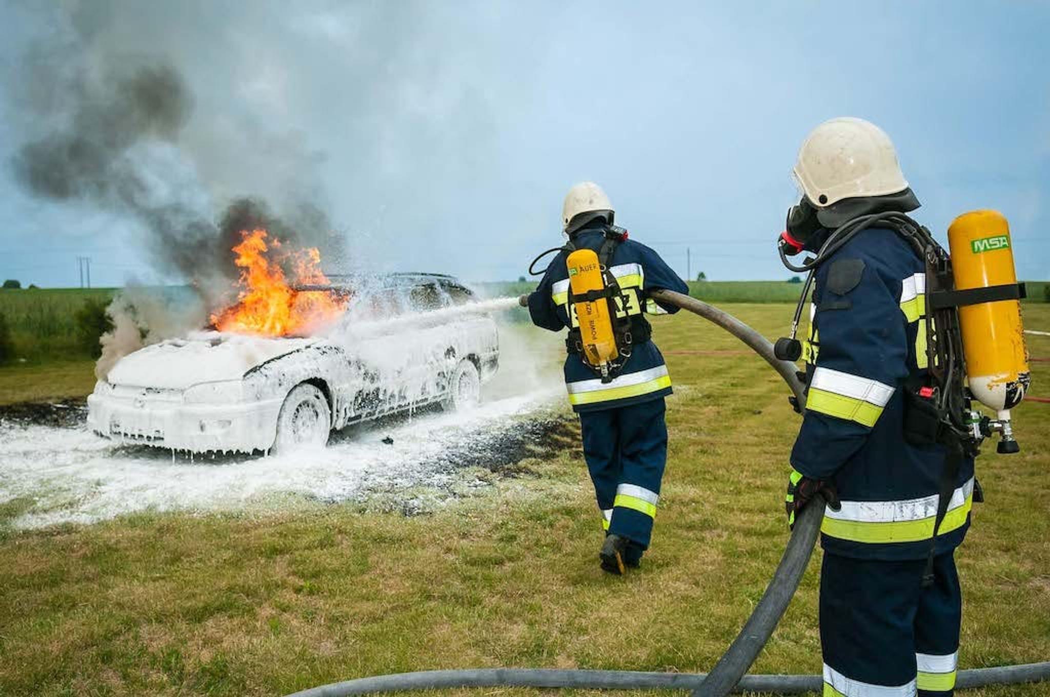 dwóch strażaków gaśnie pożar samochodu