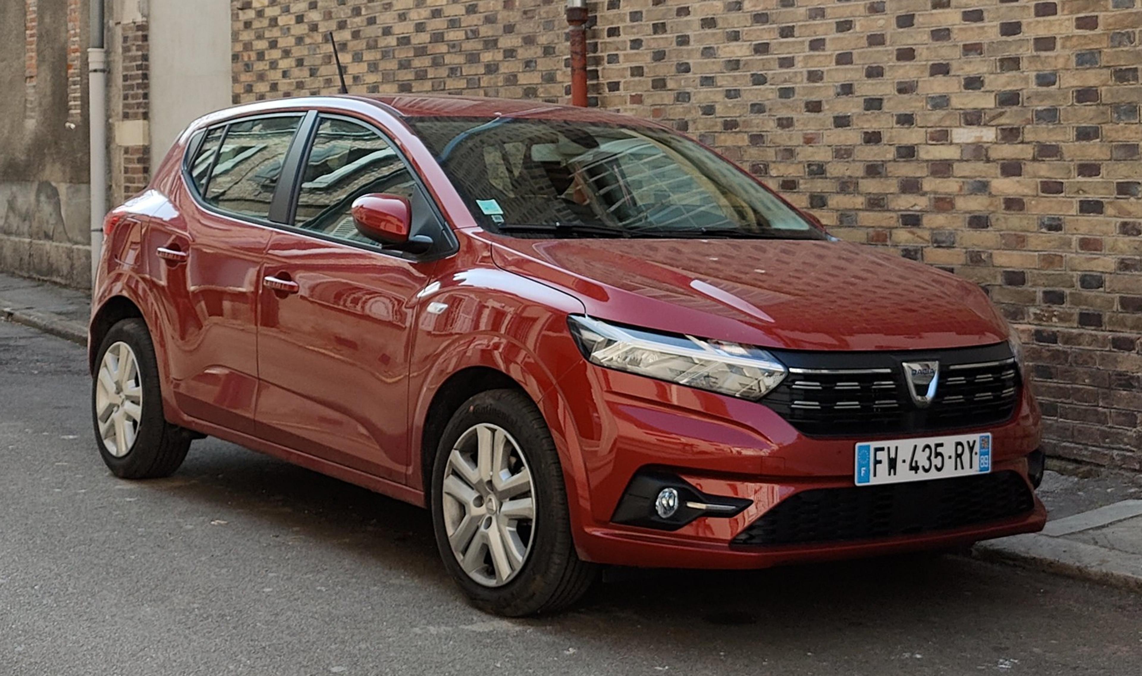 Ein roter Dacia Sandero, geparkt an einer Mauer
