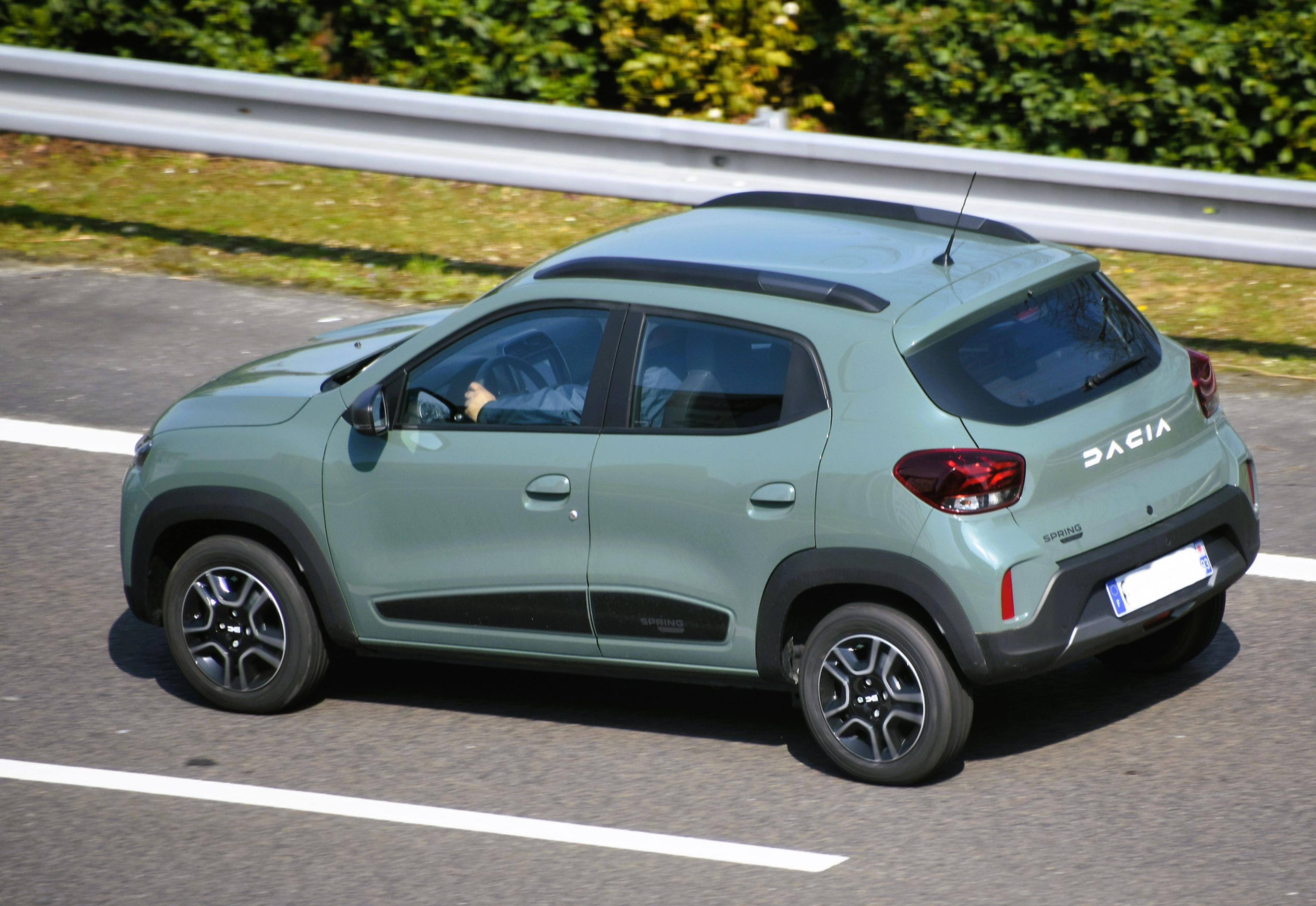 A green Dacia Spring being driven on the road