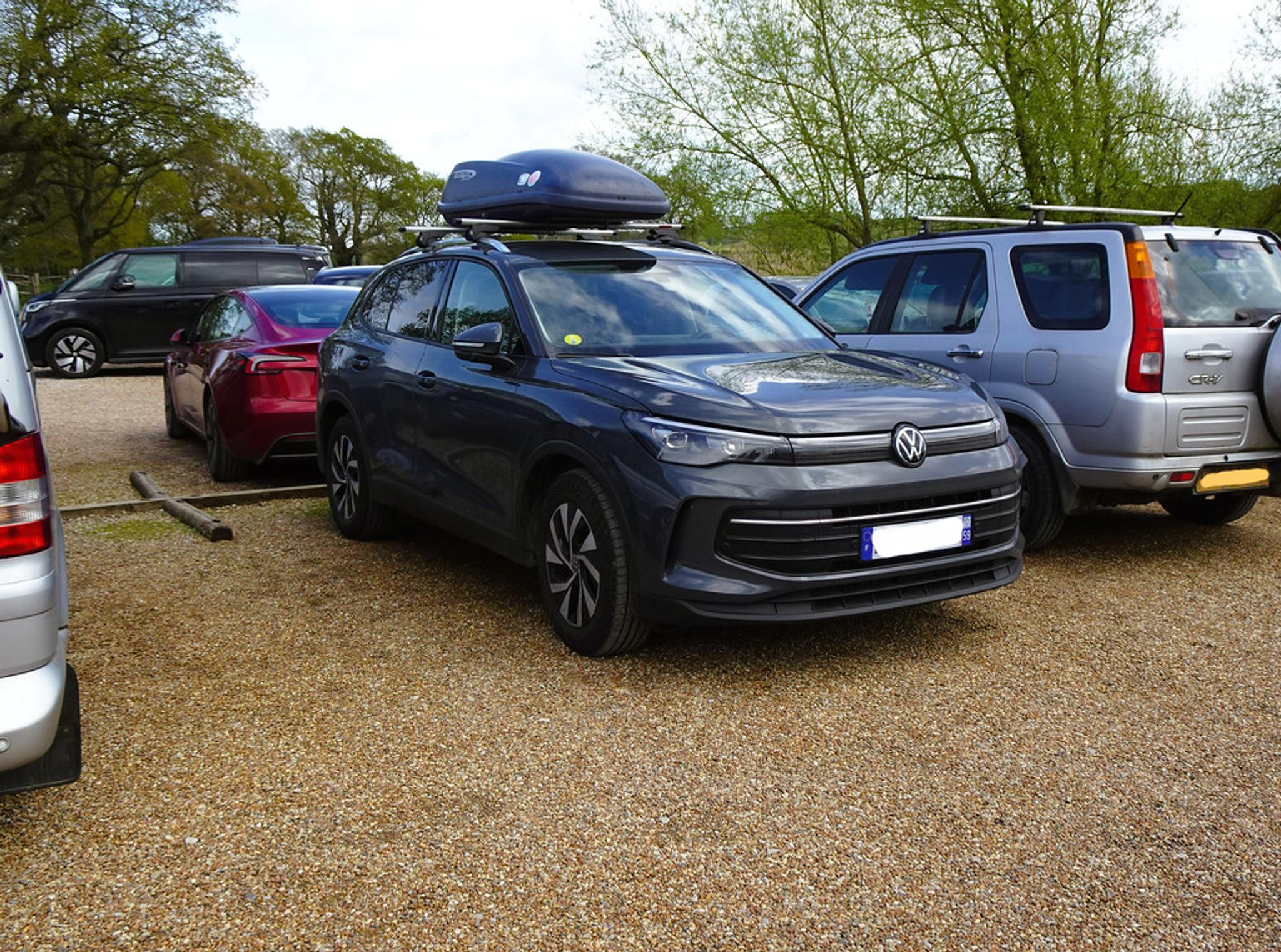 Schwarzer VW Tiguan mit Dachbox auf Kies geparkt