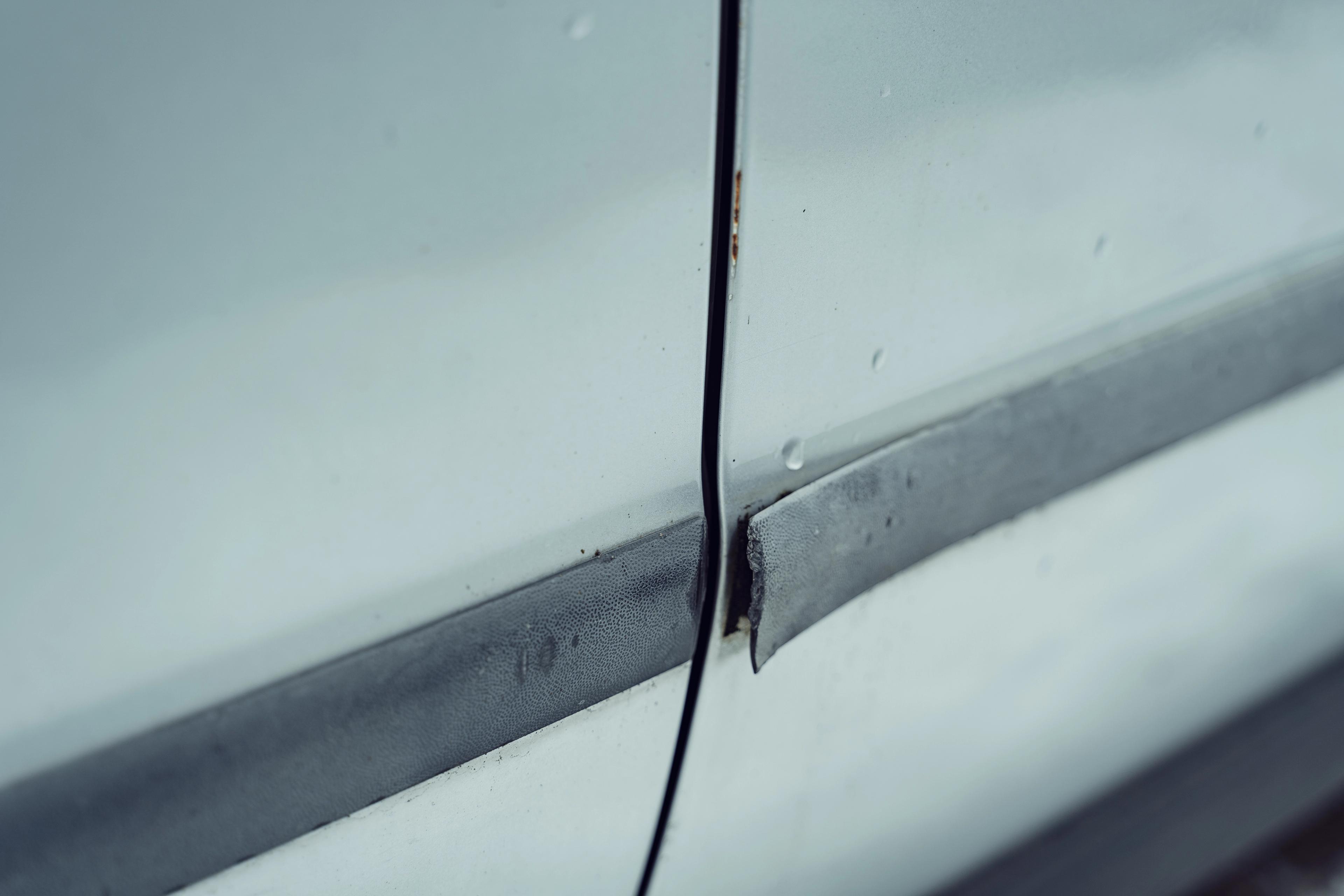 Gros plan d’une voiture grise montrant une pièce détachée avec corrosion en formation.
