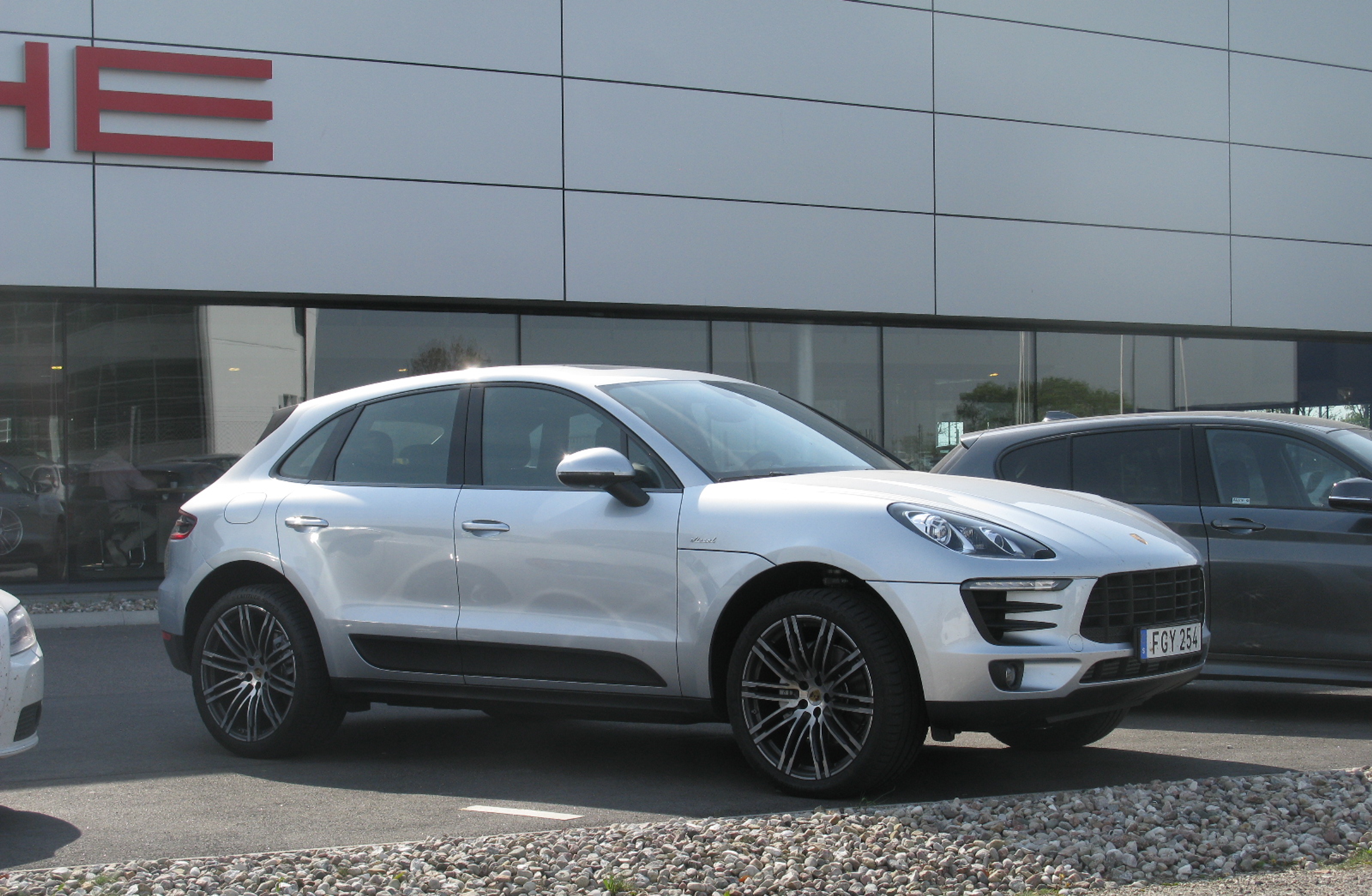 Une Porsche Macan grise garée près de la concession