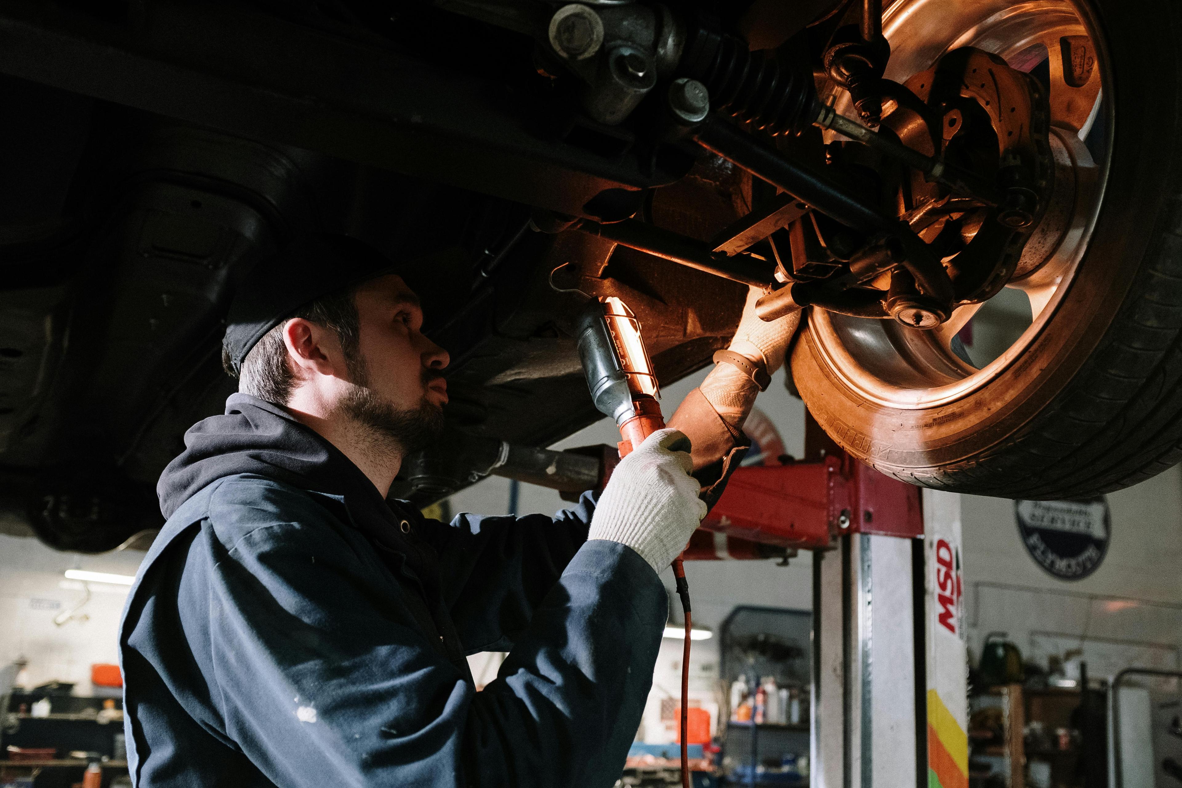 Man in a blue uniform repairing a car