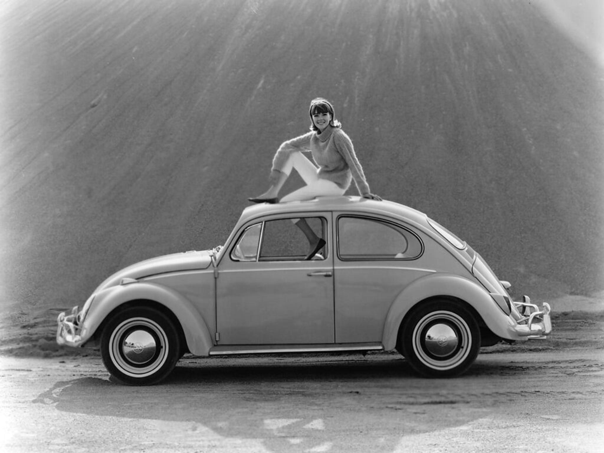 Woman sitting on the roof of Volkswagen Beetle