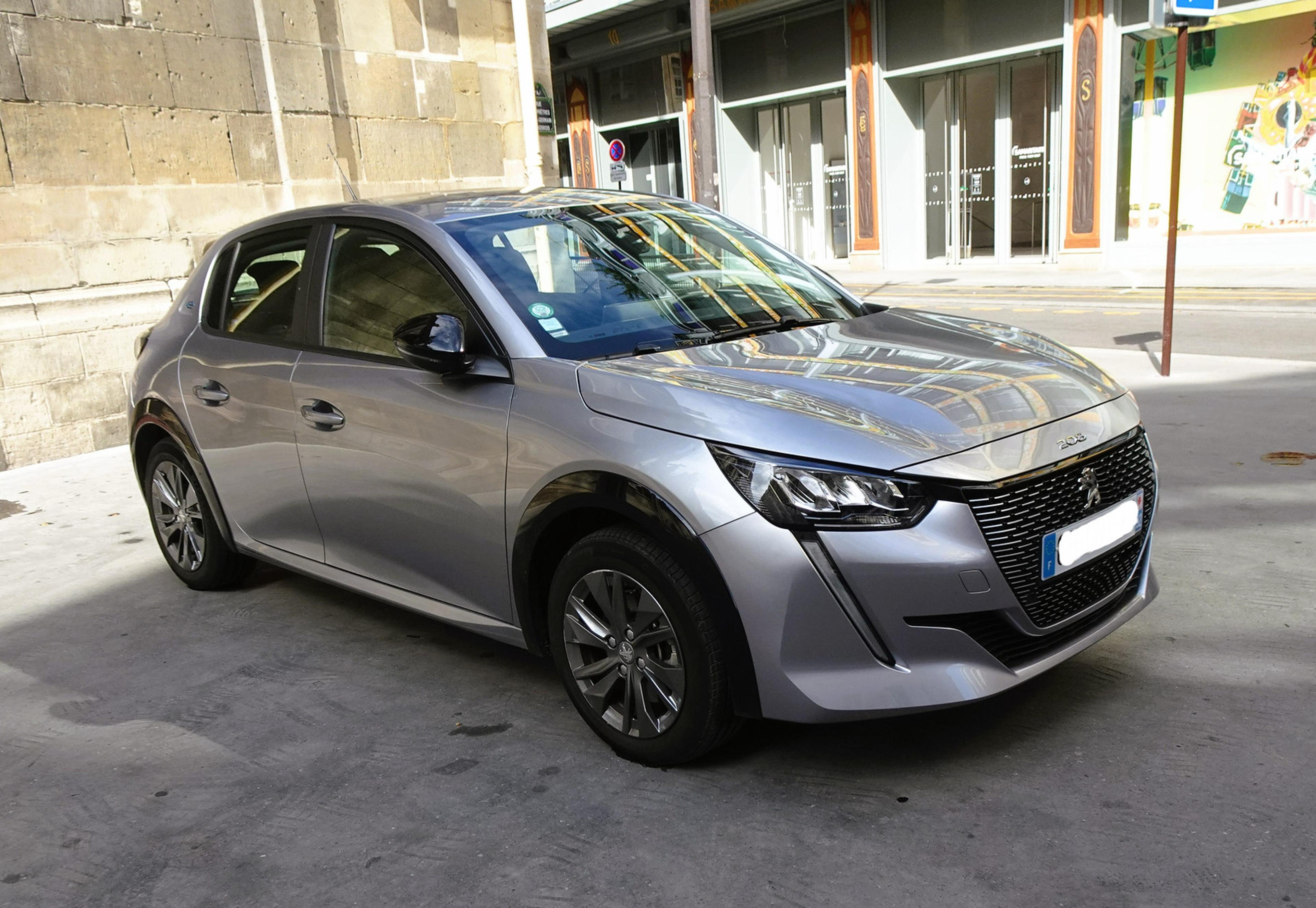 A grey Peugeot e-208 electric car parked outside