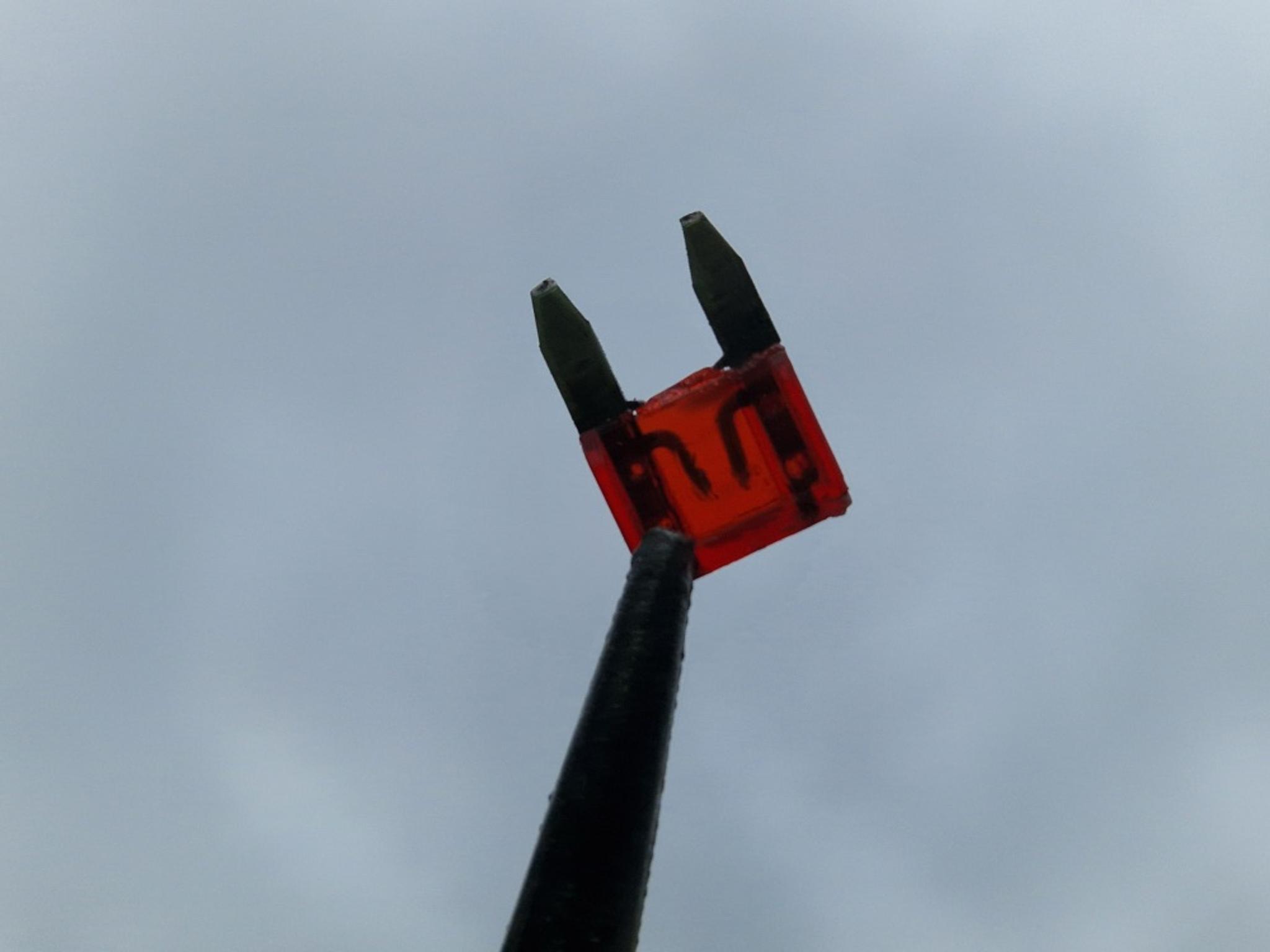 O siguranță arsă de 10 amperi este ținută cu un clește