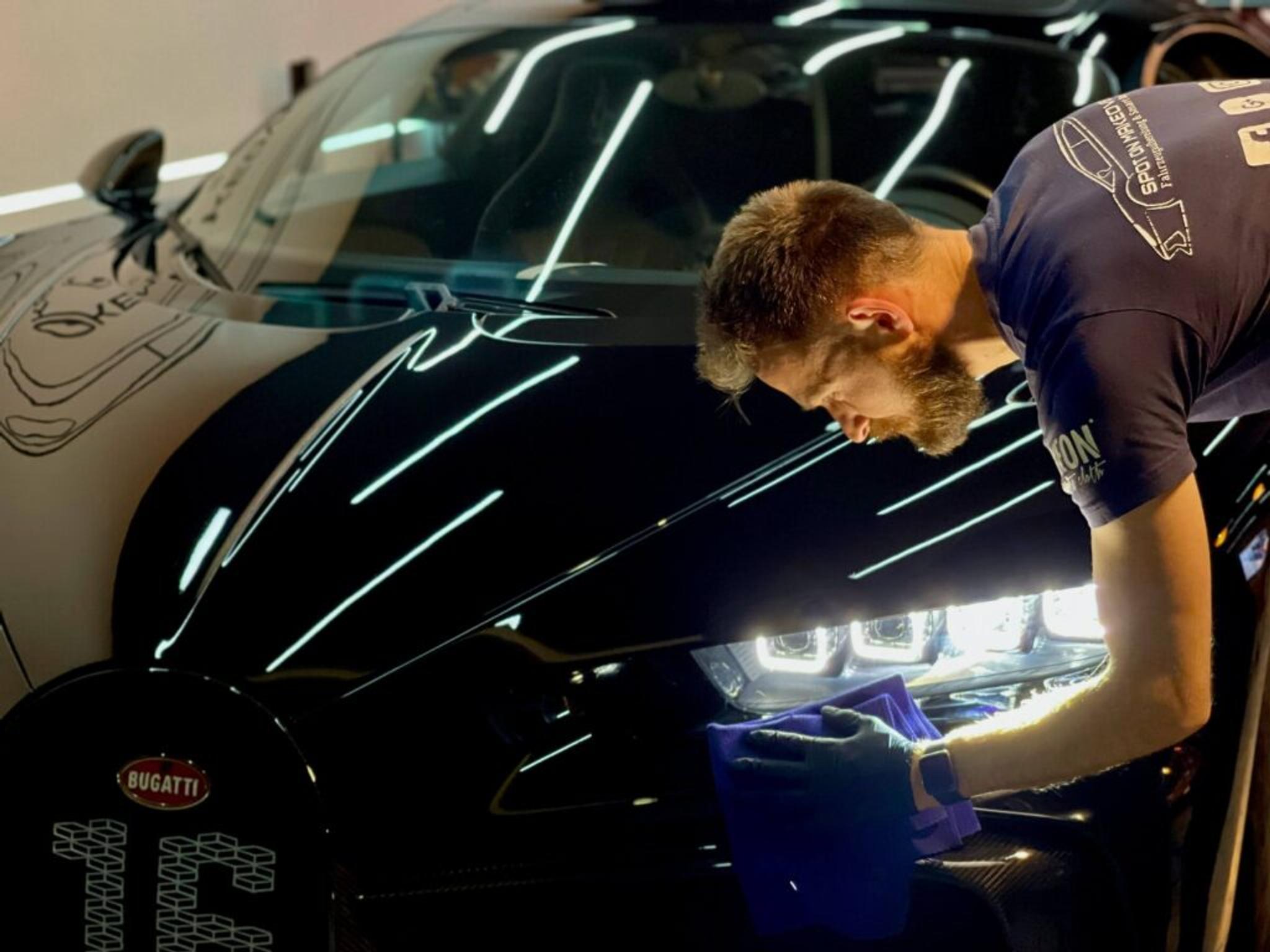 Man with a beard polishing headlights of Bugatti Chiron