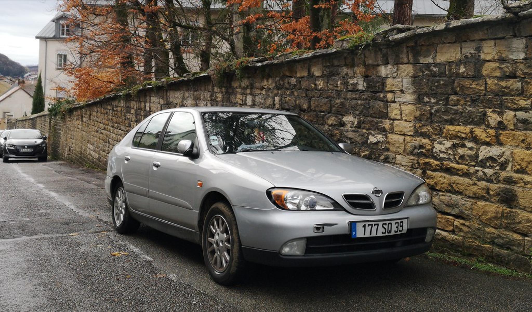 Silver Nissan Primera parked by the wall
