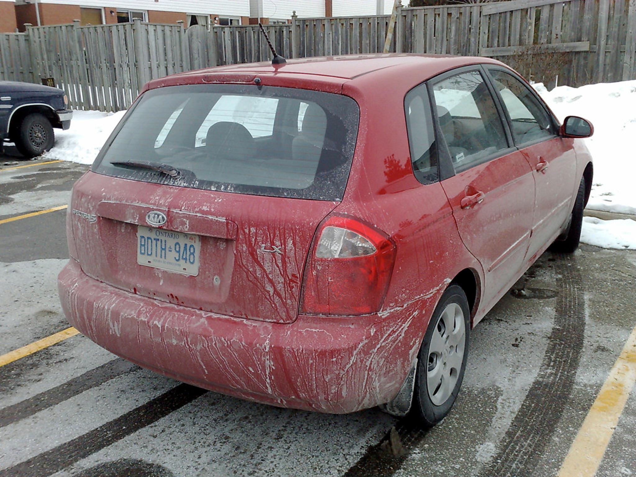 car covered in salt, winter salts on road, kia spectra, red kia