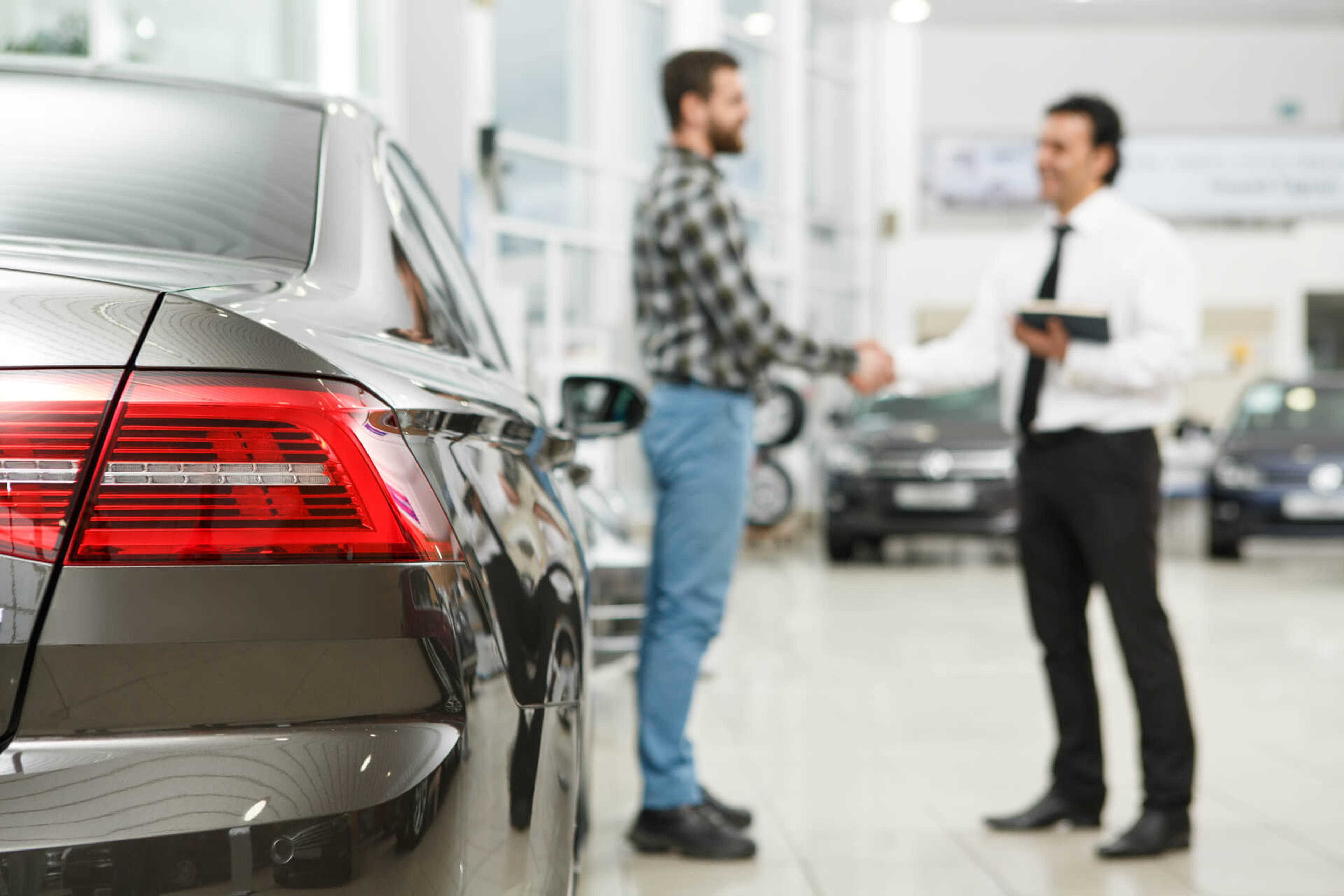 Buyer shaking hands with car salesman