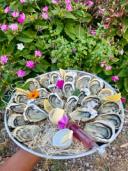 Plateau d'huîtres ouvertes, dressé avec des fleurs comestibles et un quartier de citron
