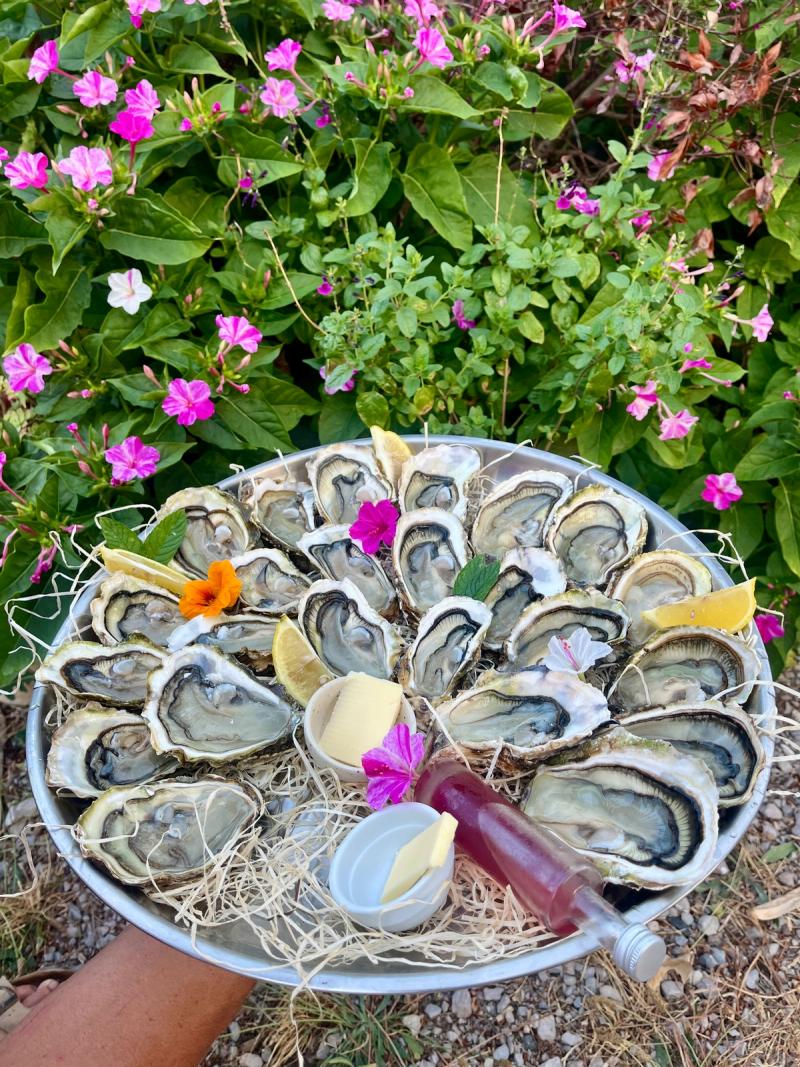 Plateau d'huîtres ouvertes, dressé avec des fleurs comestibles et un quartier de citron