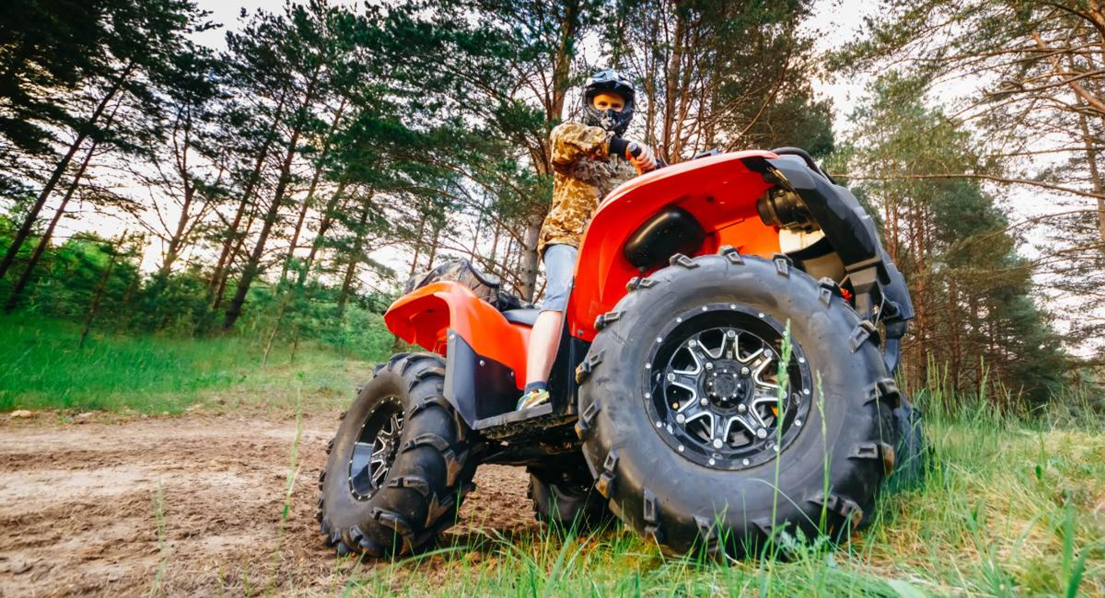 Red ATV parked on private rural property with large tires, illustrating where riders can operate without mandatory state ATV insurance requirements