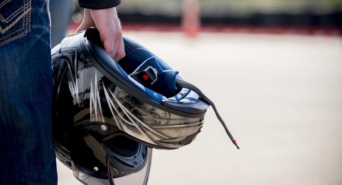 Motorcyclist holding protective helmet demonstrating motorcycle insurance claim processing timelines and safety gear coverage