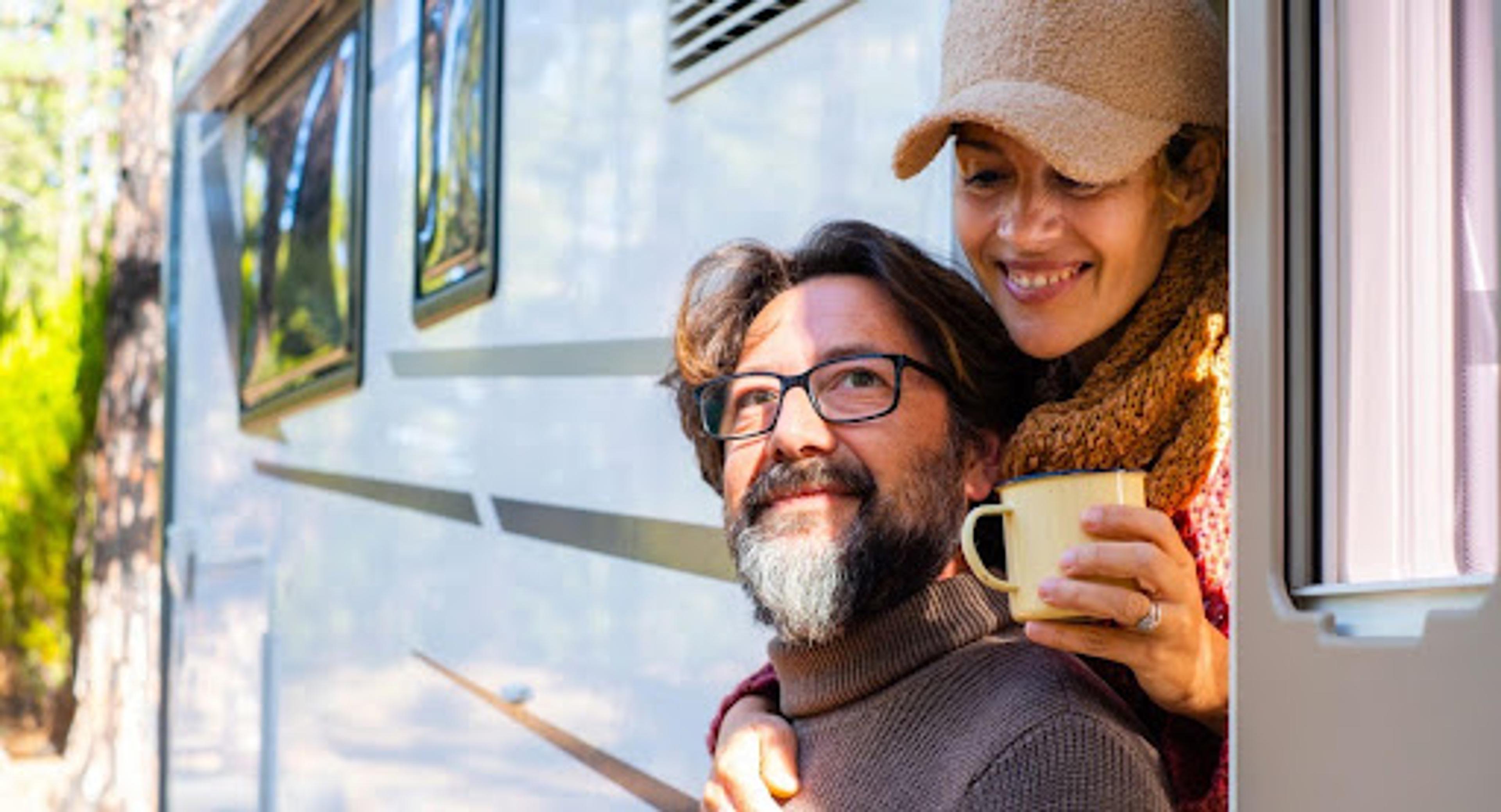 Happy couple enjoying morning coffee from Class C RV showing comfortable full-time RV living.