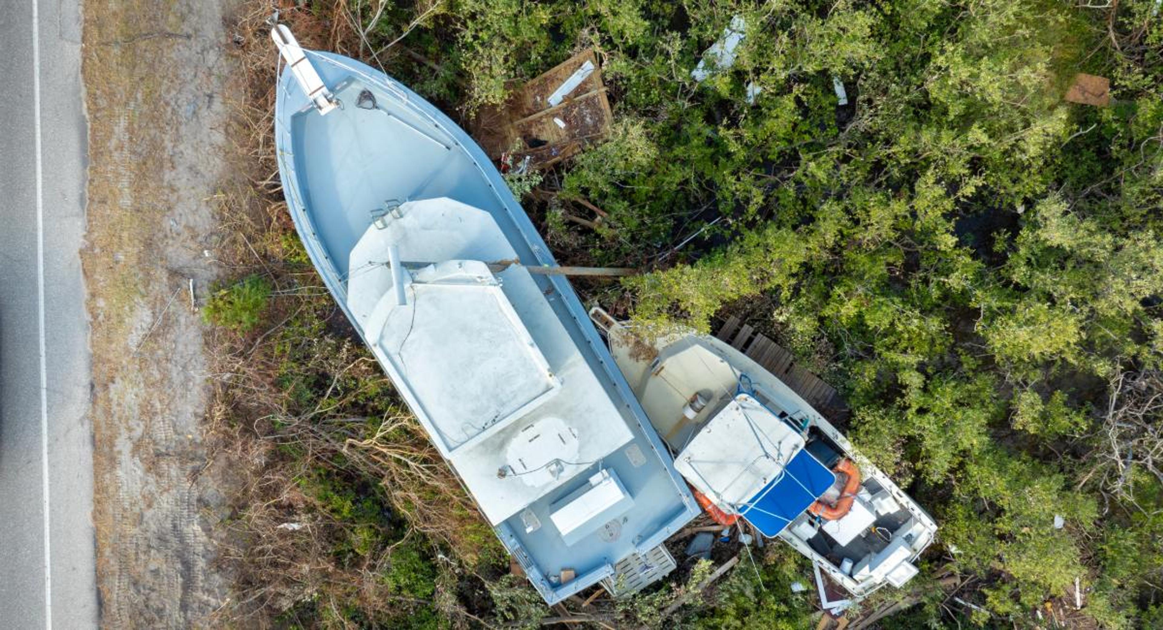 Aerial view of two boats stranded in coastal trees after a hurricane, illustrating the aftermath of storm damage and the importance of hurricane boat insurance coverage.