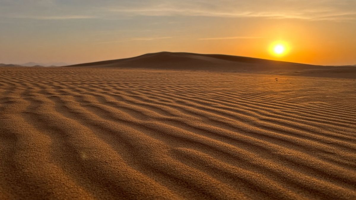 Low-angle view of sand ripples leading to a dune at sunset, a classic desert photography composition