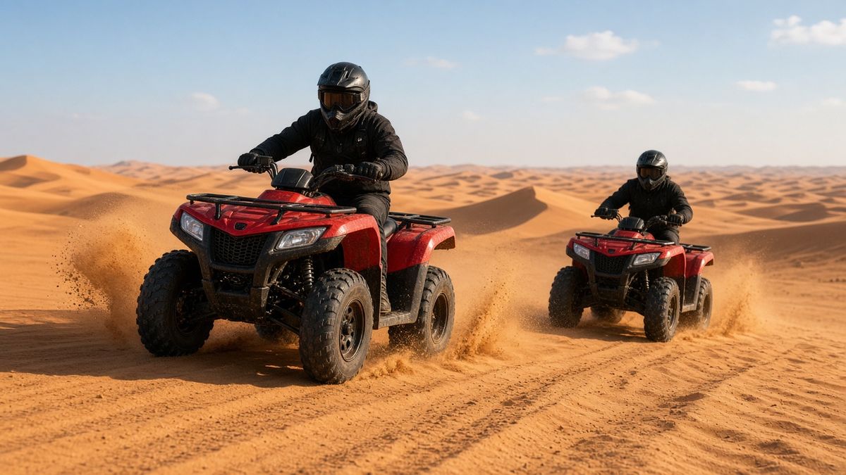 Two riders on quad bikes crossing orange sand dunes near Dubai