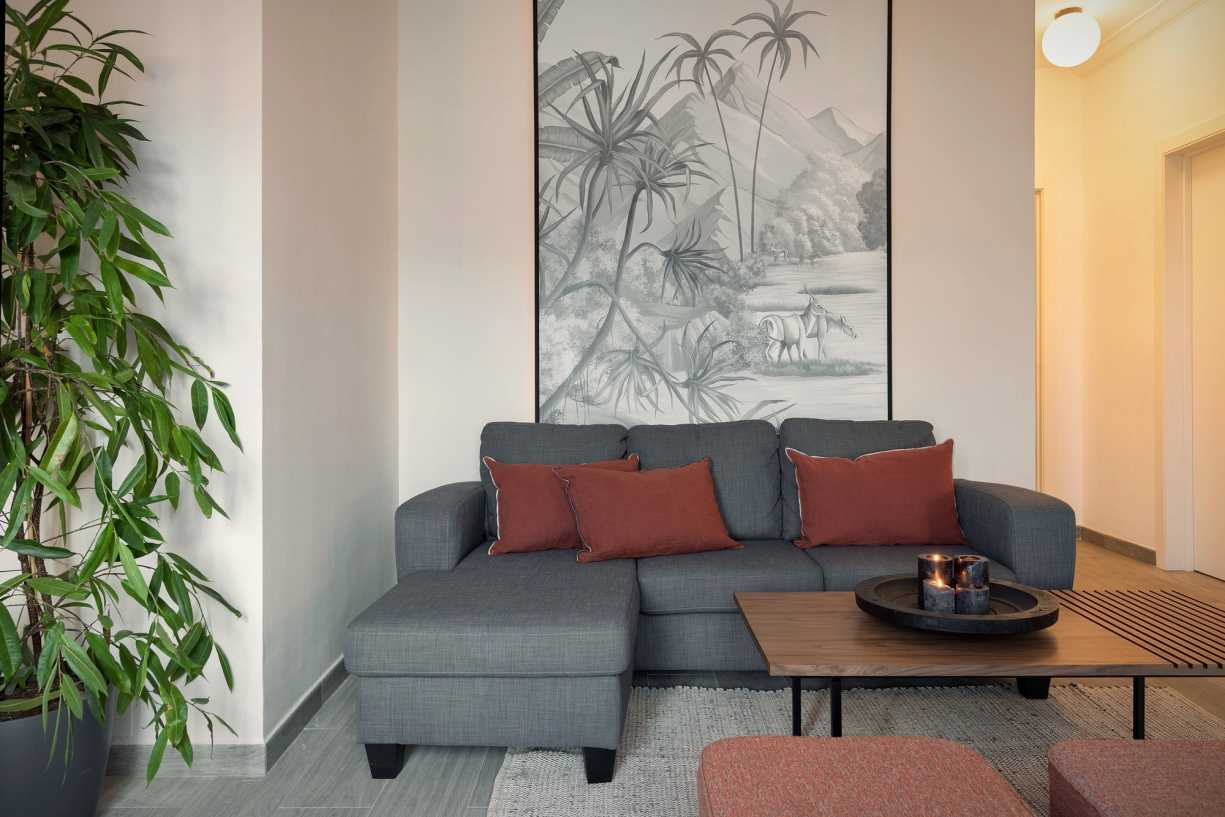 1653908891-living-room-with-sofa-and-candles-jungle-drawing-on-the-wall.jpg
