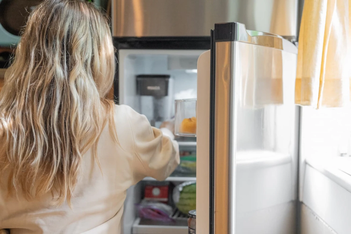 woman reaching into fridge