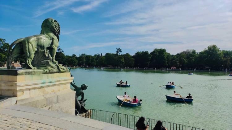 Lake with boats and a statue in Retiro Park