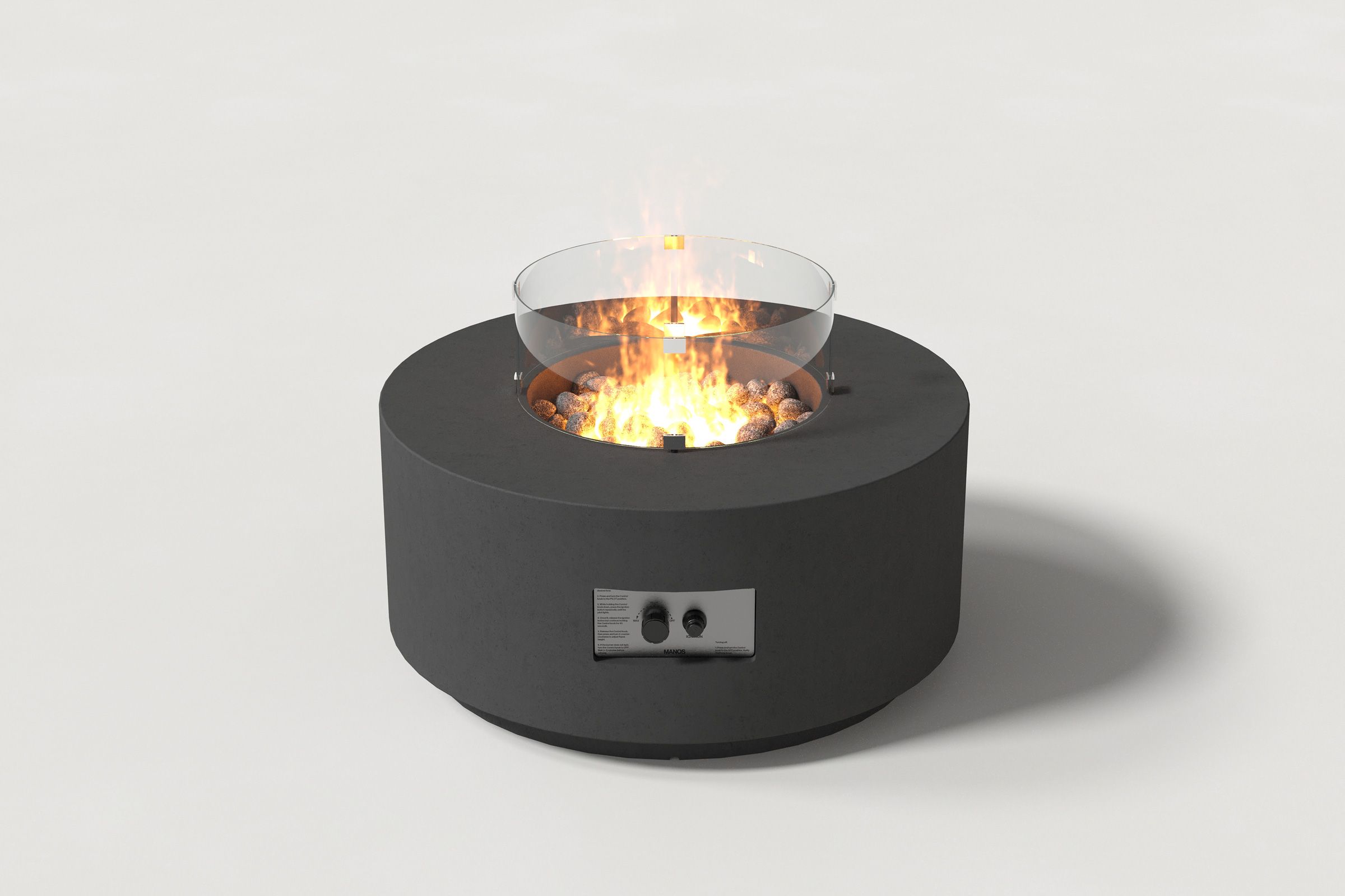 Low cylindrical charcoal colored concrete fire pit with thick walls and a central circular well filled with dark volcanic rocks and flame, with an integrated control panel, surrounded by a clear glass shield. Side view on a white background with a shadow to the right.