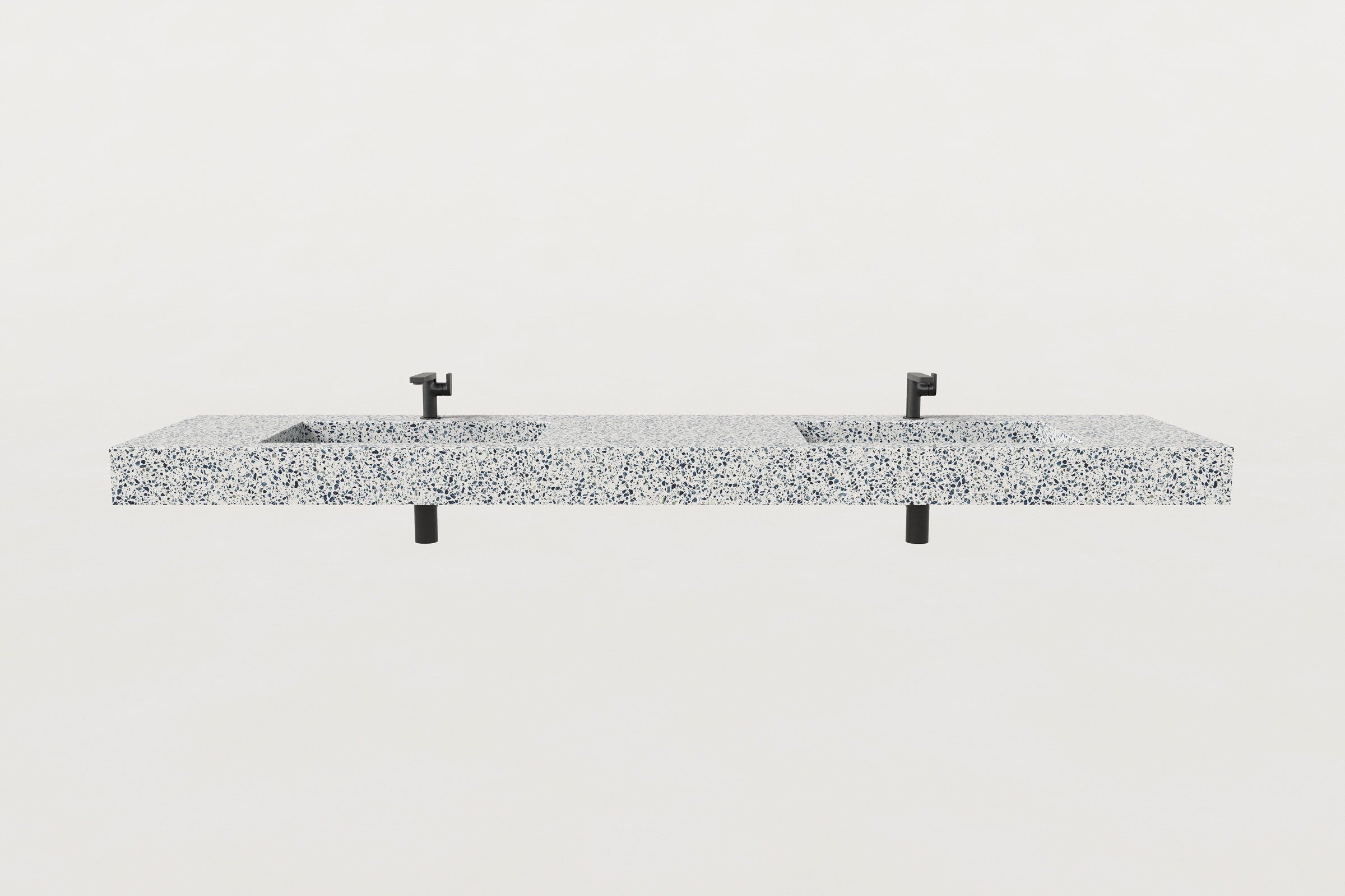 Front view of terrazzo double-basin sink with two matte black faucets and drain pipes visible.