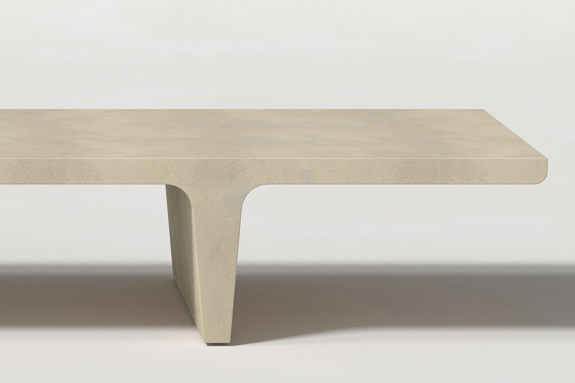 Close-up of a light beige concrete coffee table with sculptural double tee legs, highlighting soft edges and subtle surface texture against a clean white background.