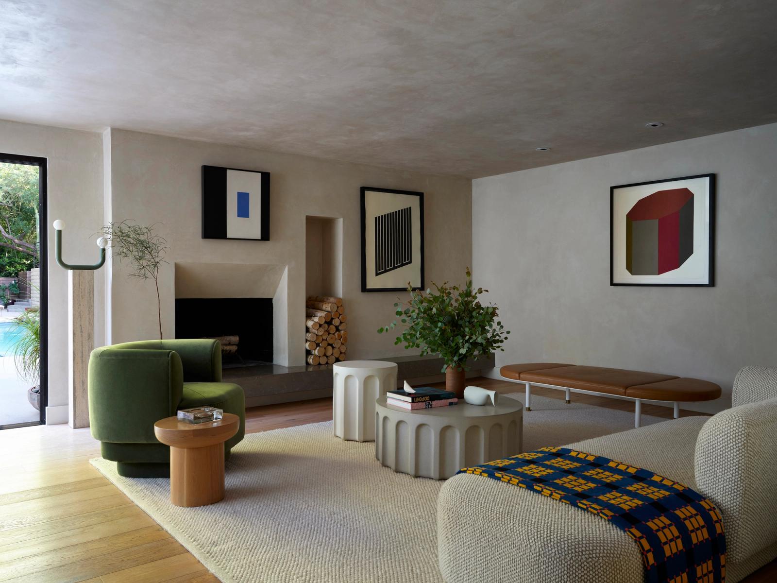 Contemporary living room with fluted white concrete tables, geometric art, green accent chair and built-in fireplace. Light wood floors, cream run and plaster walls.