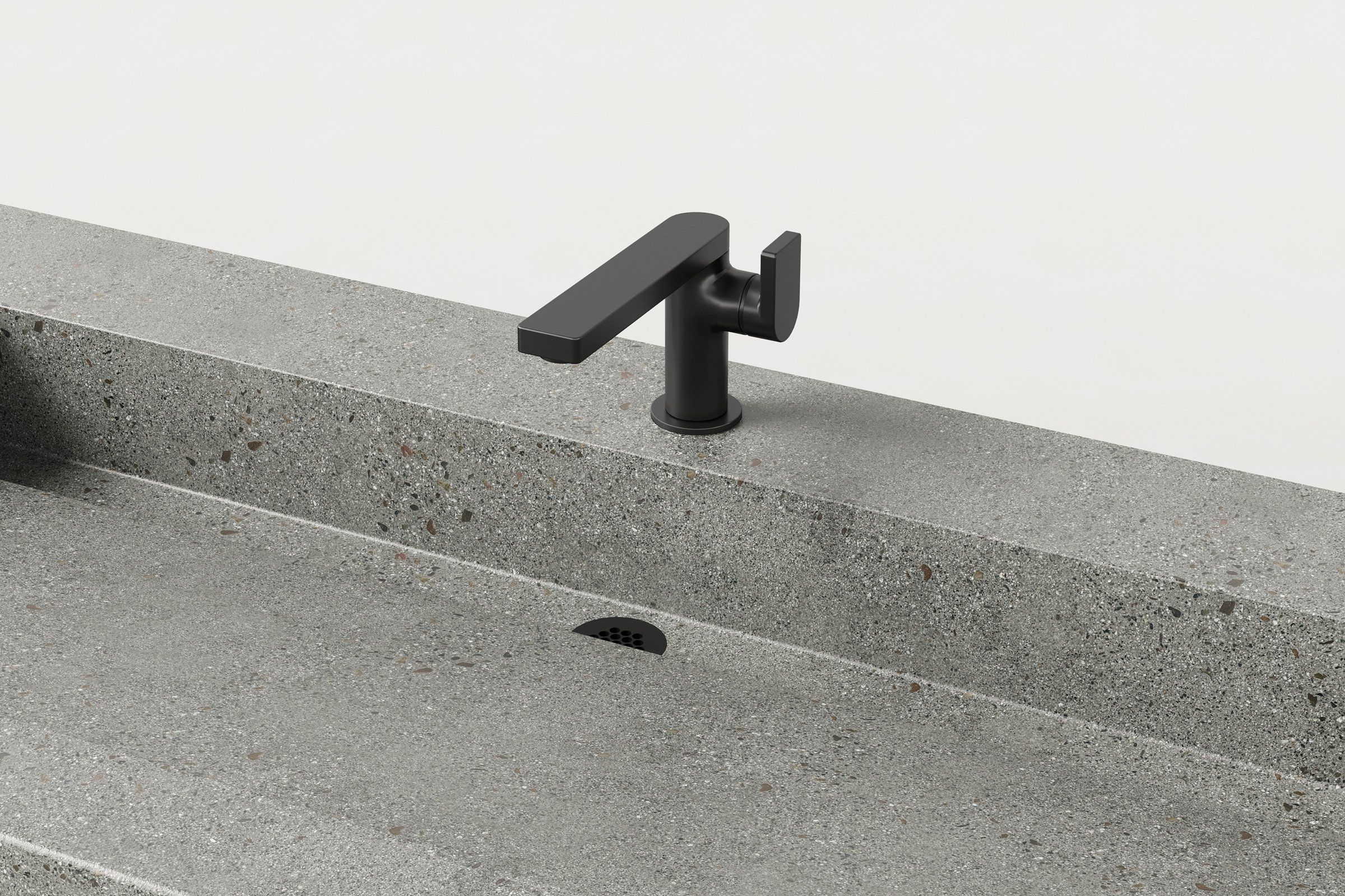 Close-up of matte black faucet mounted on Manos Trof Flow 60 concrete sink in Juda finish with integrated drain.
