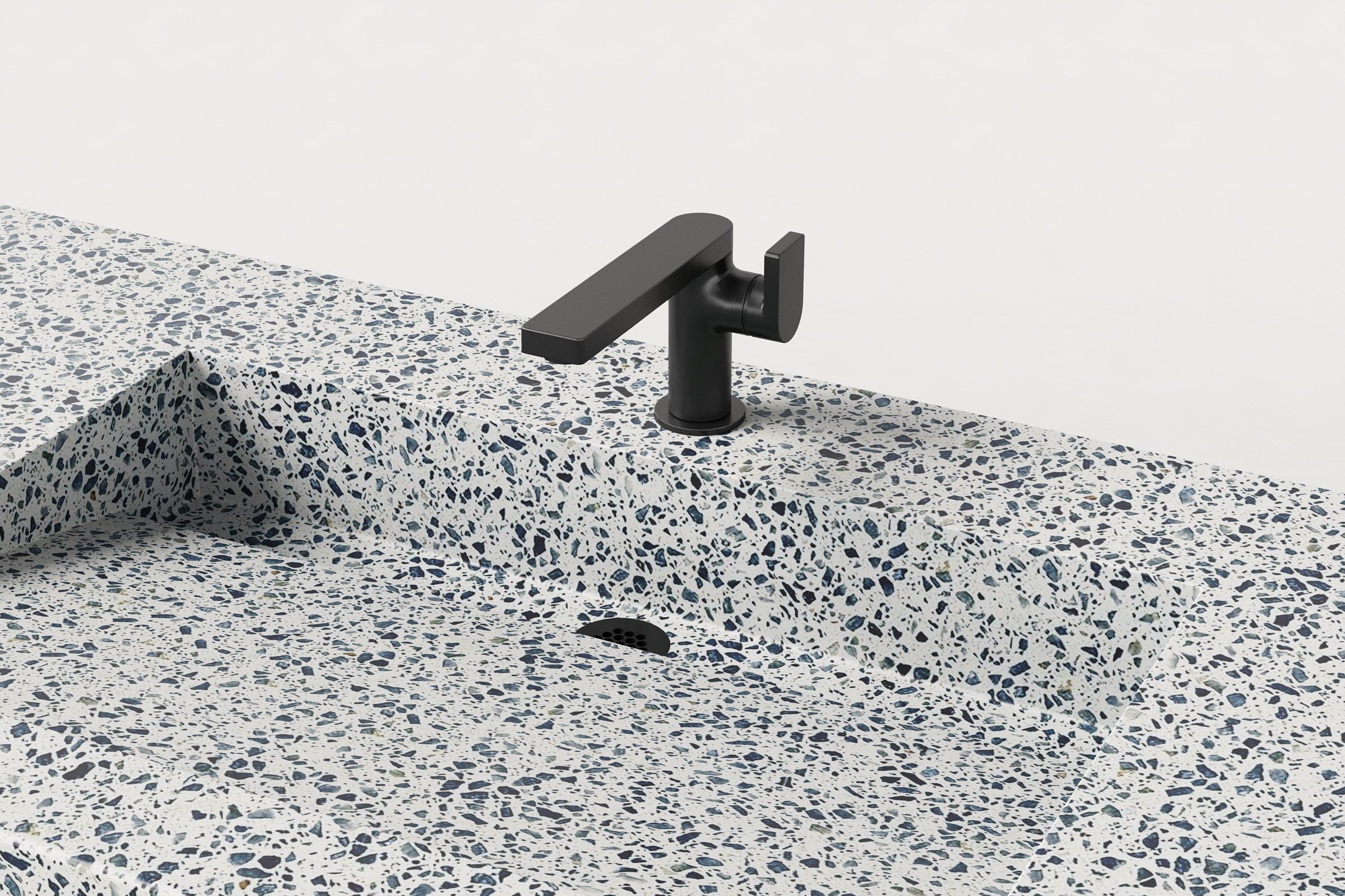 Detail view of the Unazzo finish terrazzo sink basin with matte black faucet and integrated drain.
