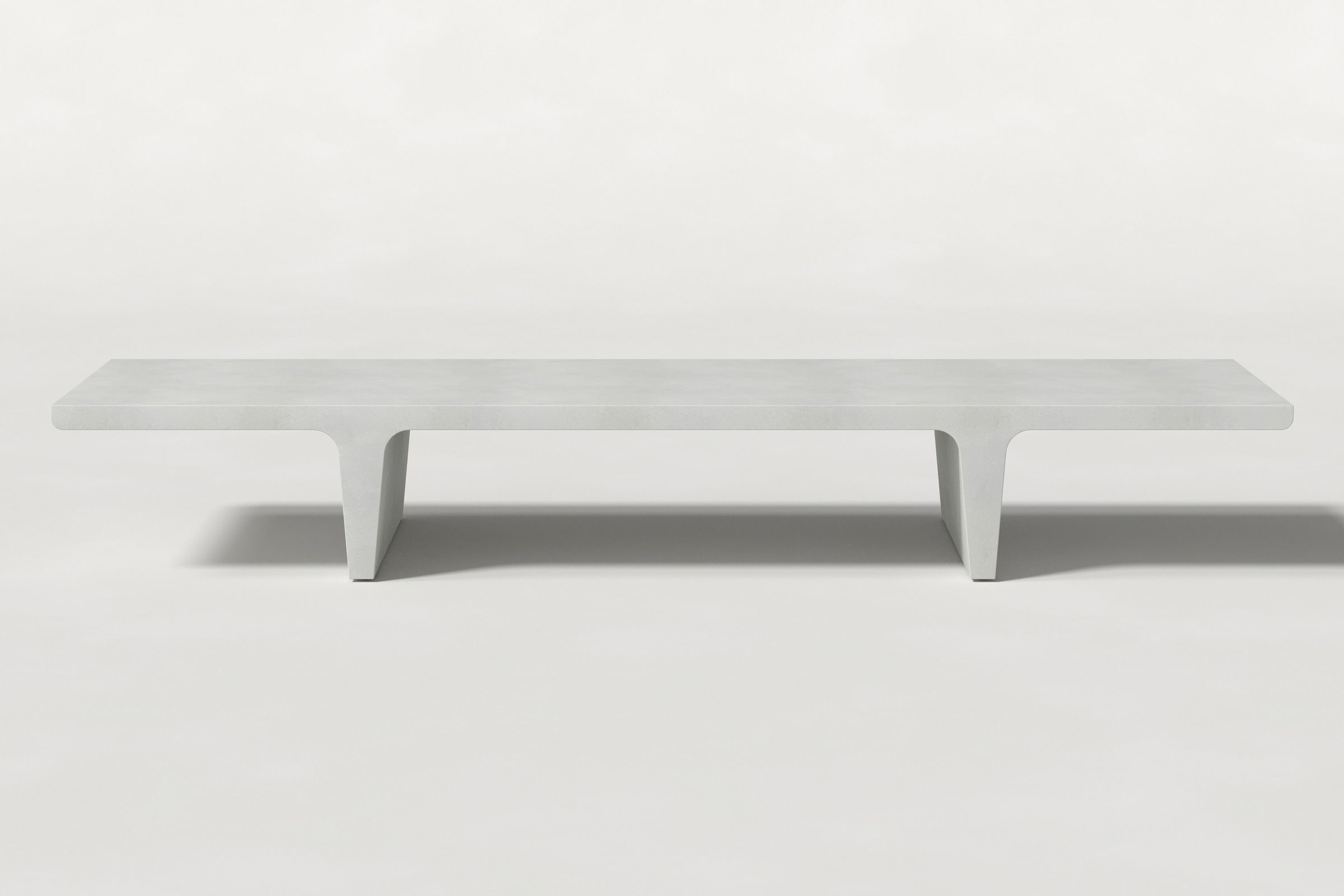 Long rectangular solid white concrete coffee table with sculptural double tee legs and a smooth top, set against a clean white background.