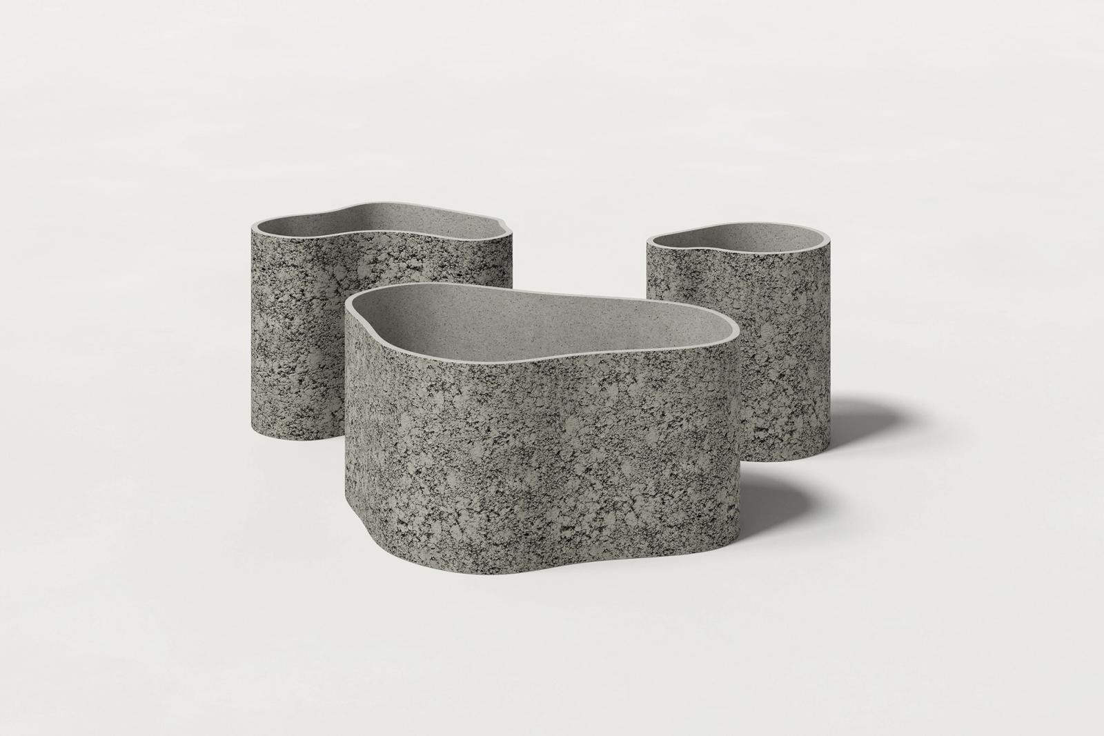 Three sizes of soft grey concrete planters with organic, textured curved exteriors & thick walls with smooth interiors shown on a white background, the largest in front.
