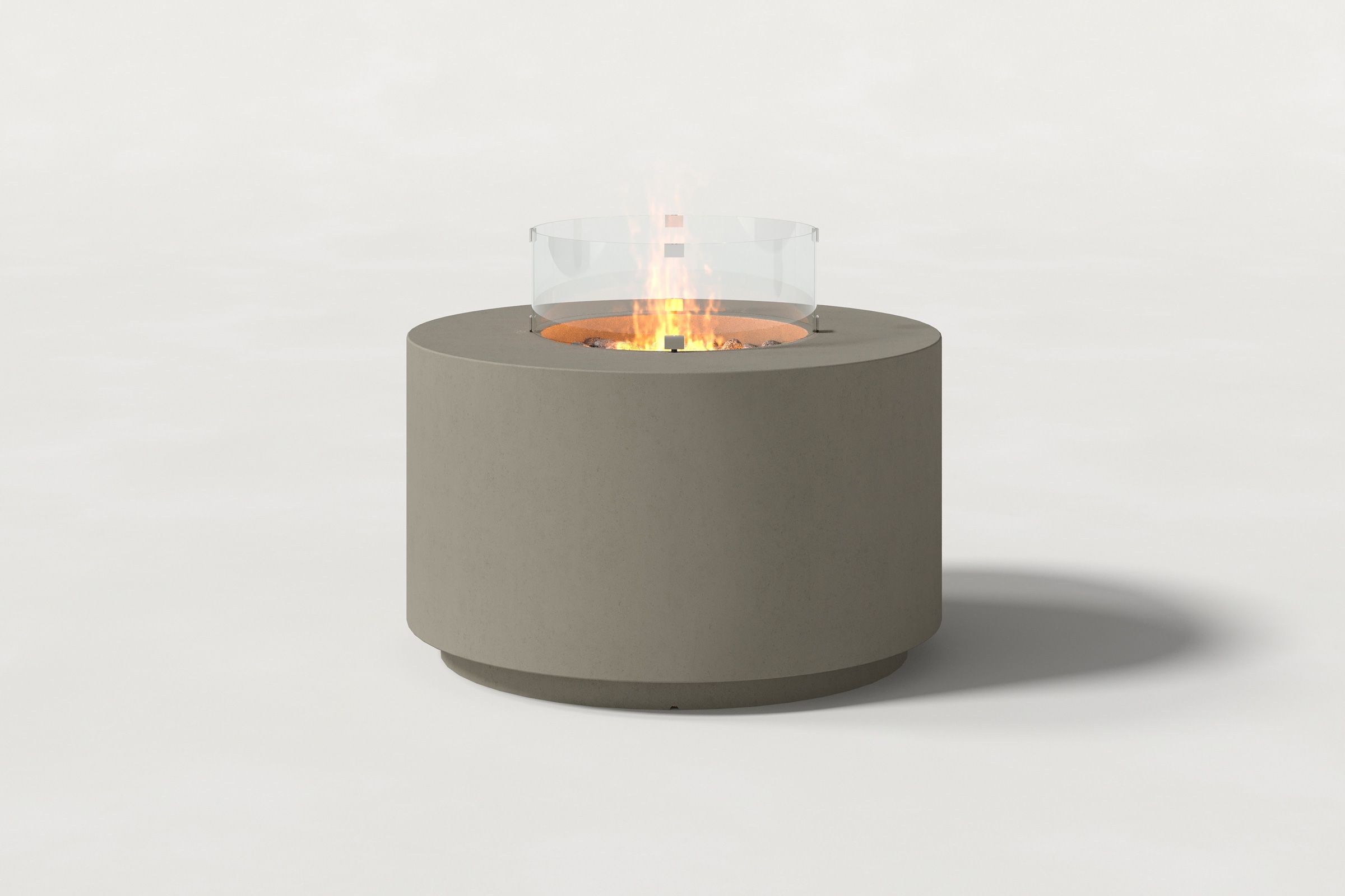 Low cylindrical dark grey colored concrete fire pit with thick walls and a central circular well filled with dark volcanic rocks and flame, featuring an glass shield. Front view on a white background.