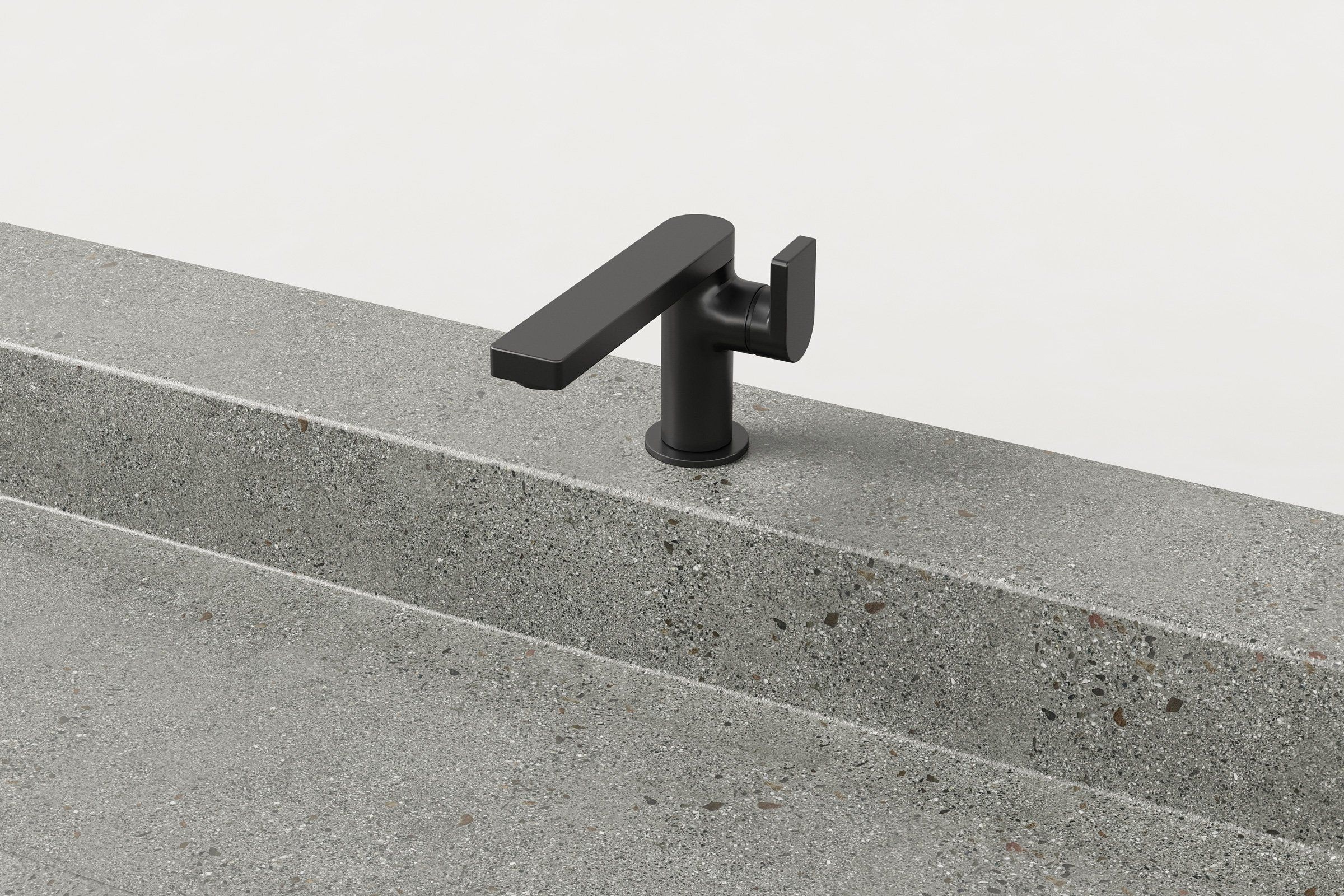 Close-up of a matte black faucet mounted on a concrete trough sink.