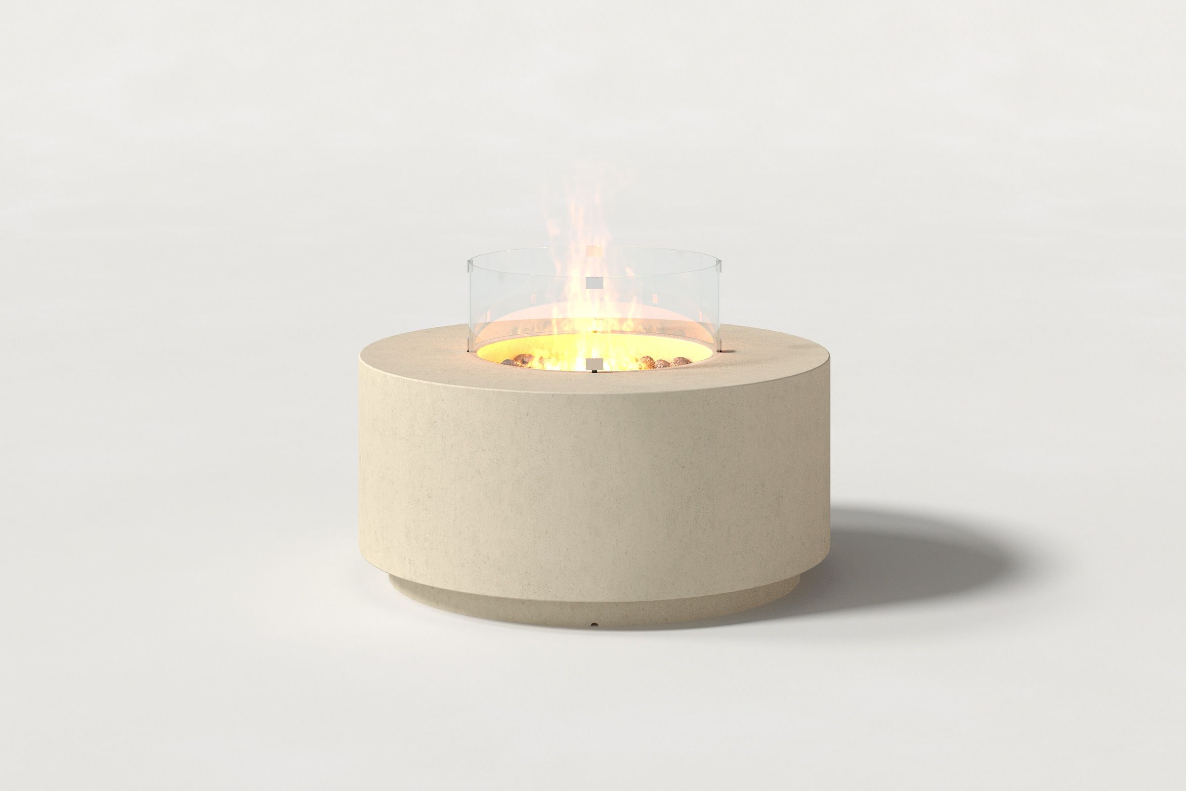 Low cylindrical sand-colored concrete fire pit with thick walls and a central circular well filled with dark volcanic rocks and flame, surrounded by a clear glass shield. Side view on a white background with a shadow to the right.