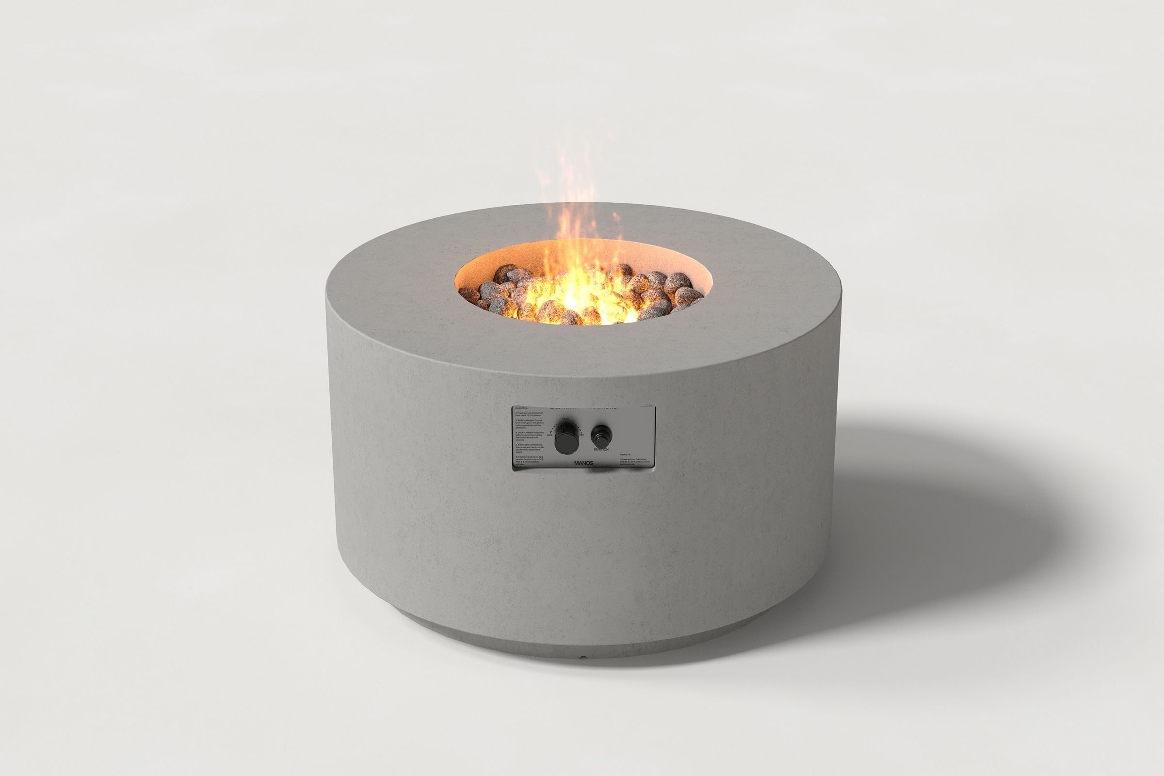 Low cylindrical grey colored concrete fire pit with thick walls and a central circular well filled with dark volcanic rocks and flame. Side view on a white background.