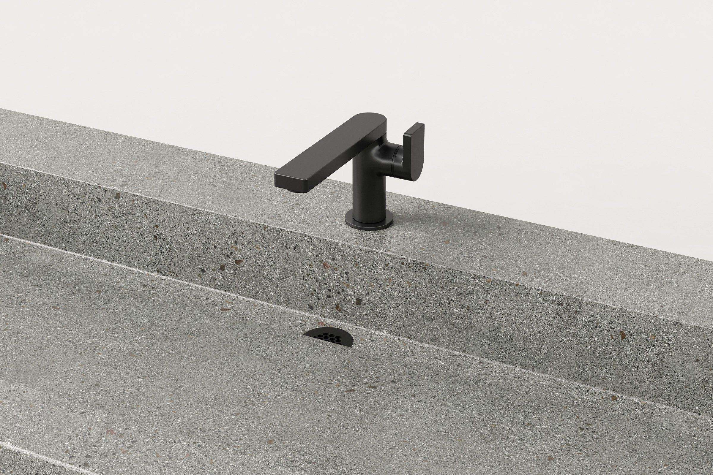 Close-up view of the black faucet and drain area on the light grey concrete sink, emphasizing the exposed aggregate surface.